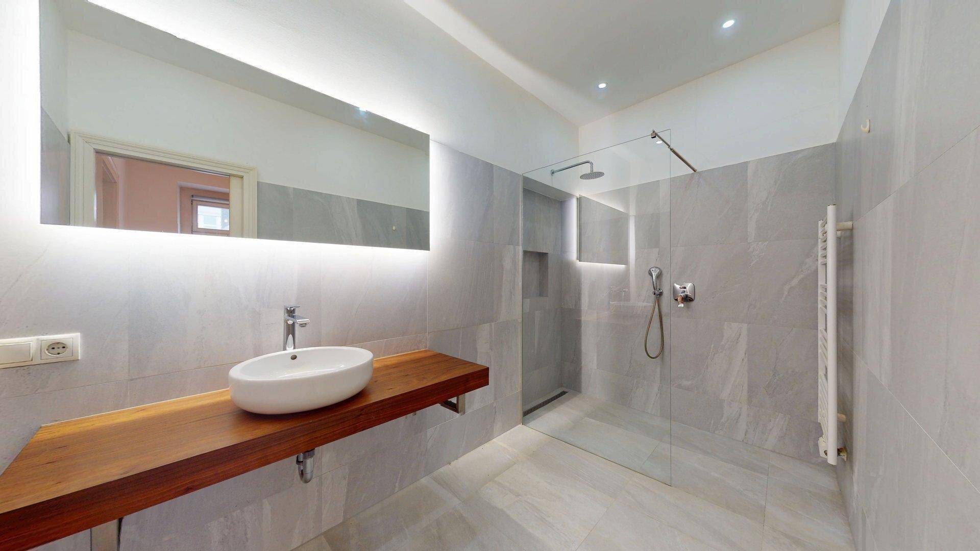 Modernes Badezimmer mit Einzelwaschbecken, großer begehbarer Dusche und beheiztem Handtuchhalter.