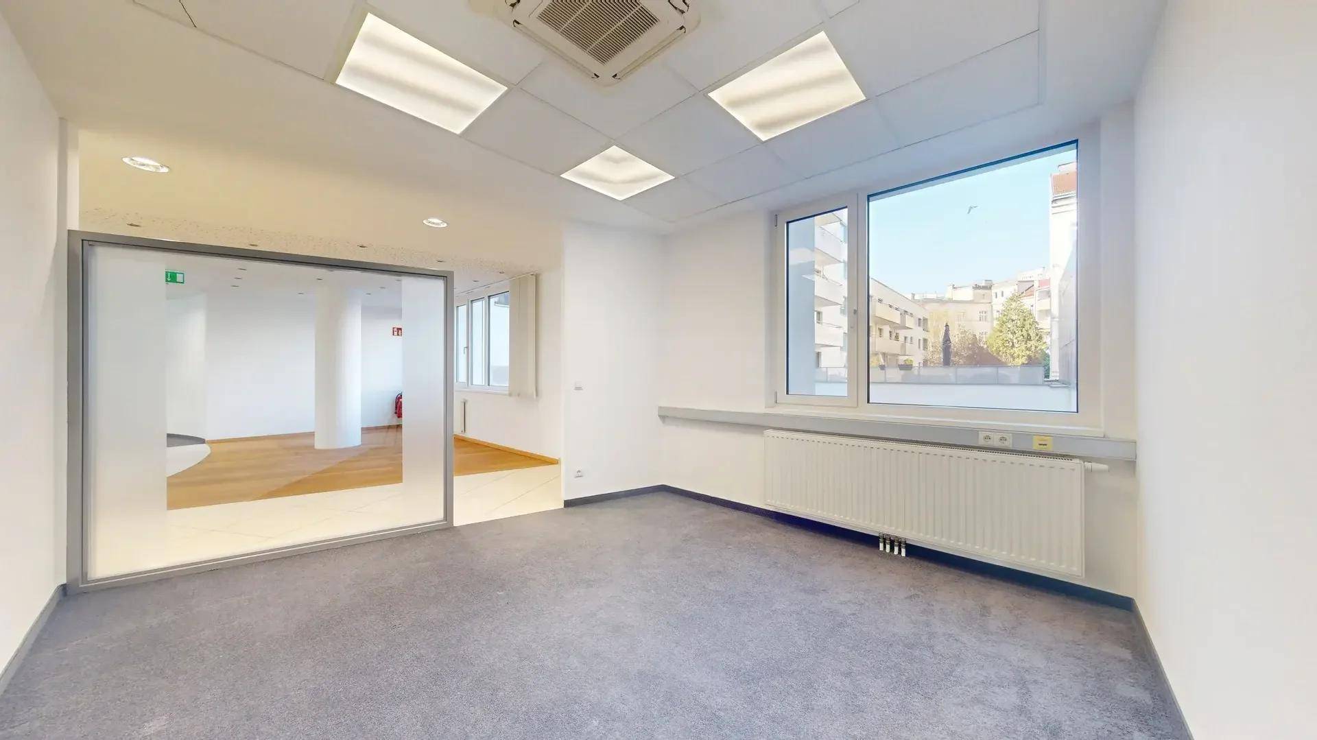 Einzelbüro mit Teppichboden, großen Fenstern und Blick auf die Stadt, ausgestattet mit Klimaanlage.
