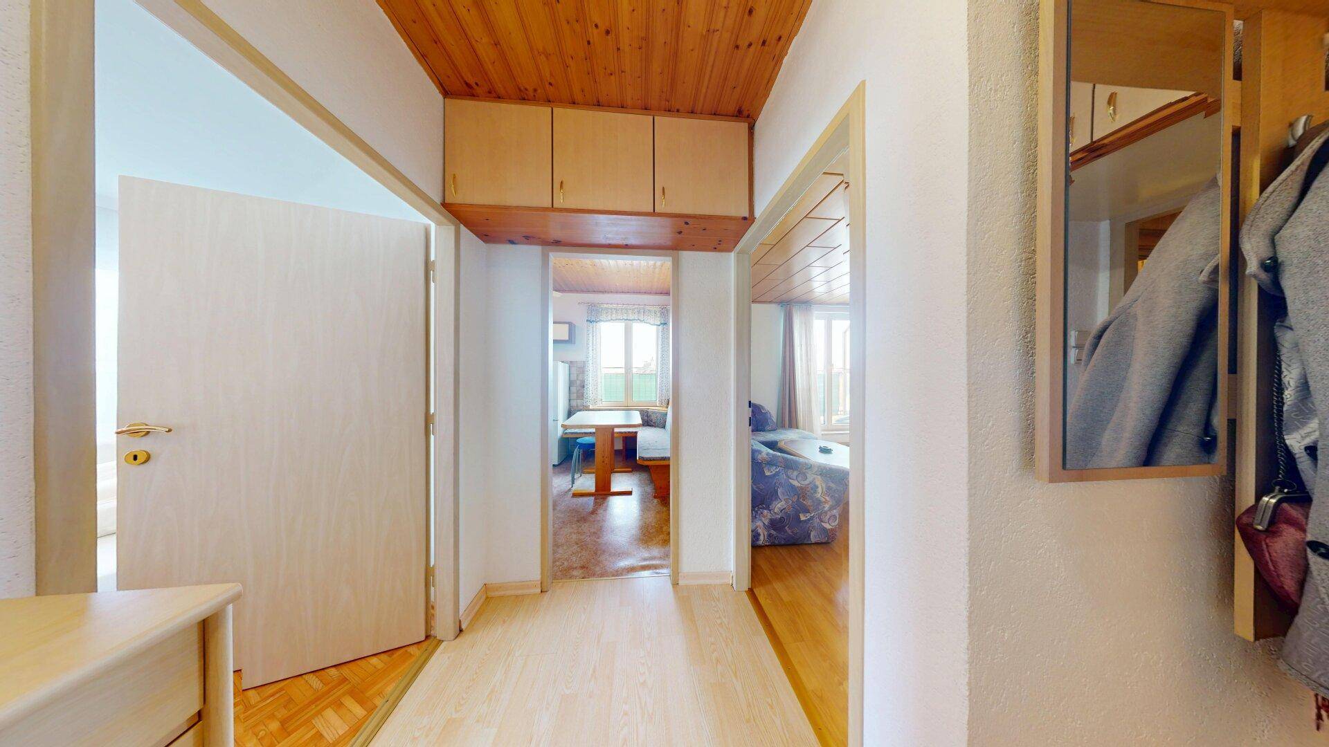 Flur mit Holzdecke und Parkettboden, der zu verschiedenen Räumen führt.