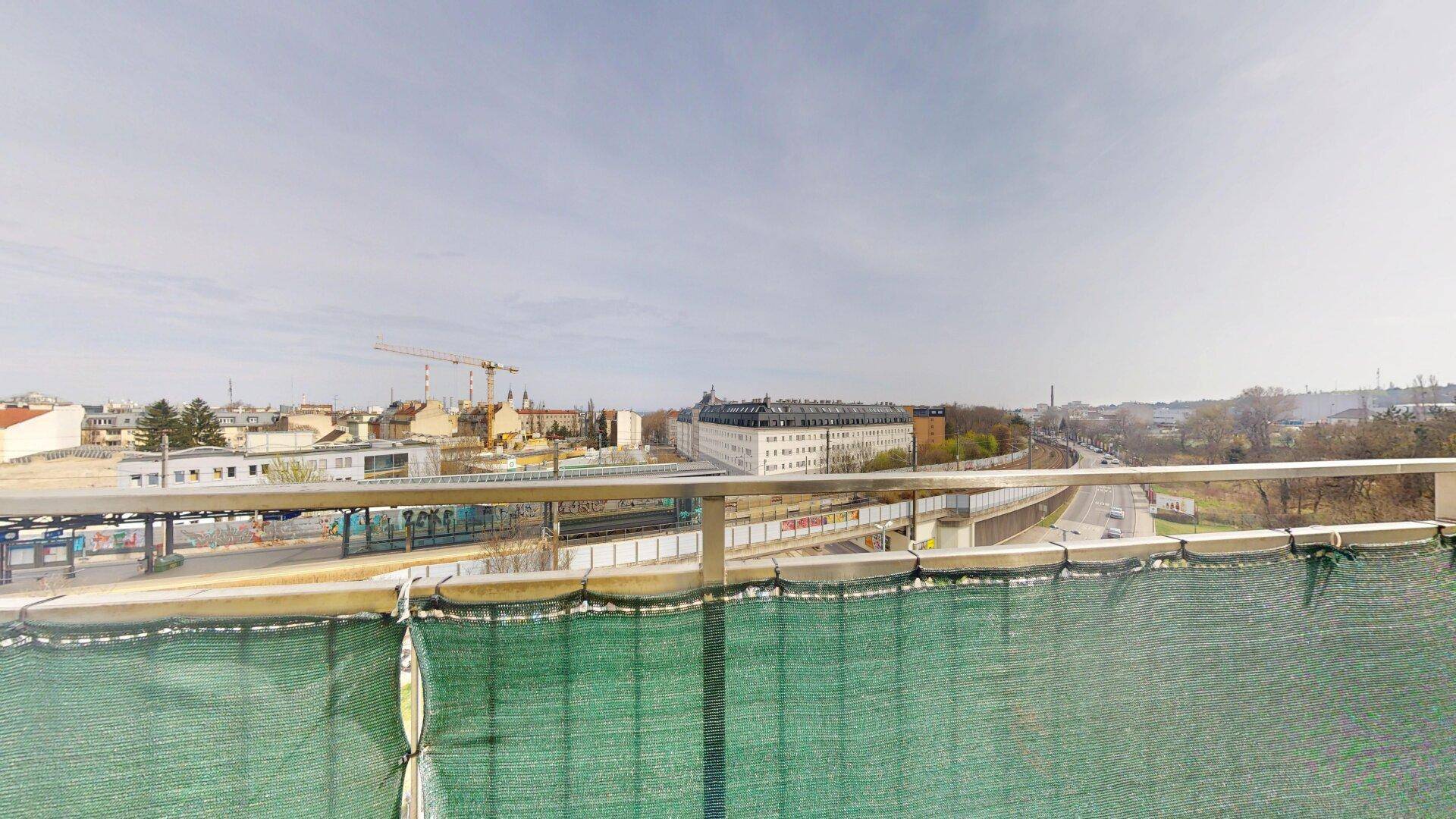 Weitläufiger Blick über die Stadt mit Bahnanlagen und Gebäuden unter bewölktem Himmel.