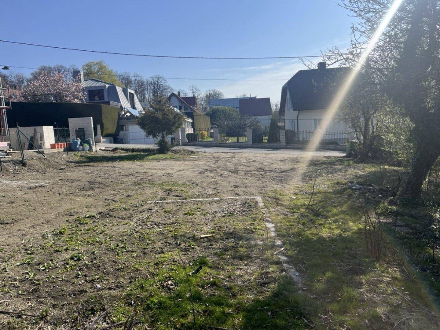 Weitläufiges Grundstück mit Blick auf benachbarte Häuser und sonnigem Himmel.