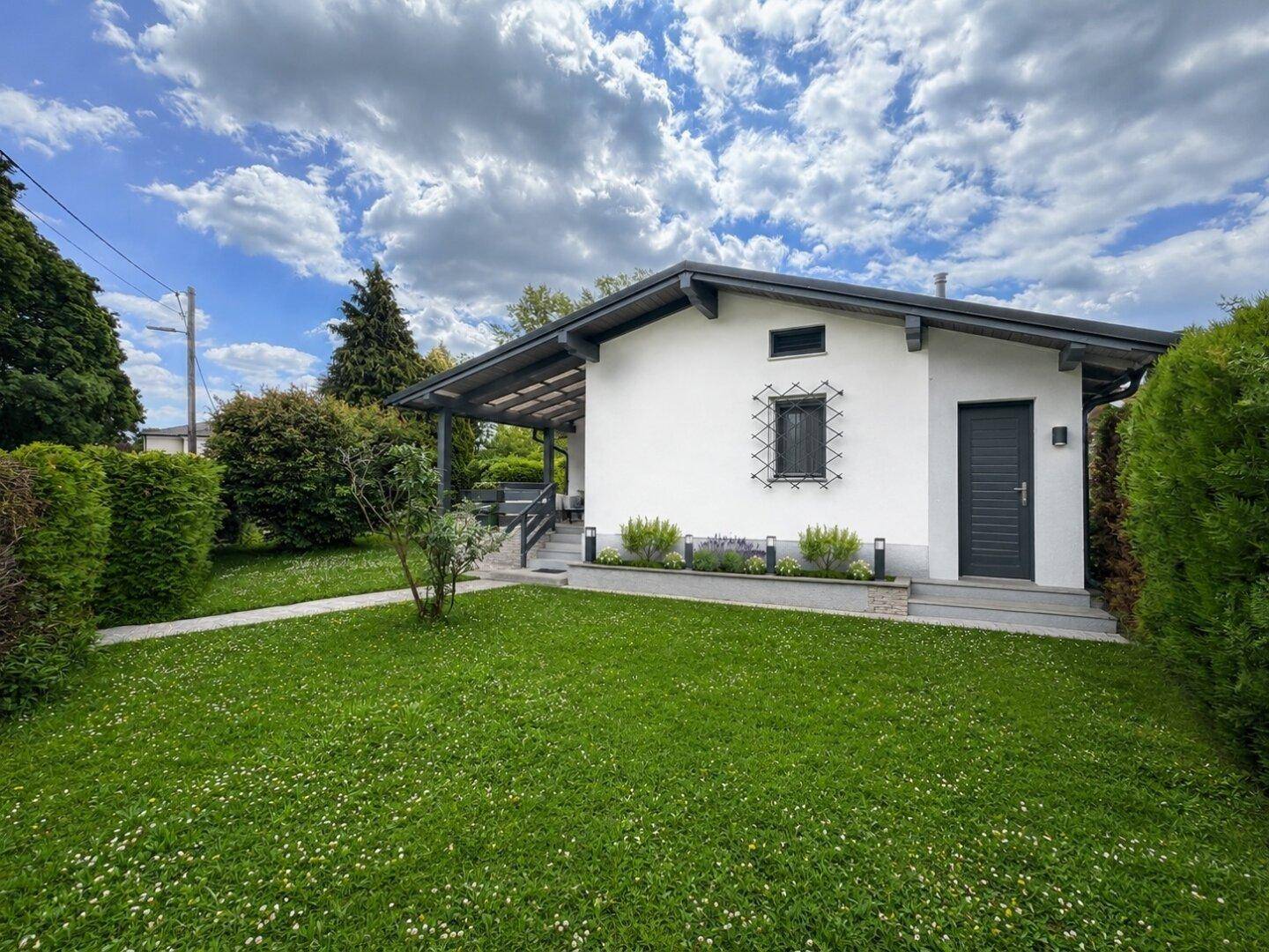 Seitenansicht des renovierten Hauses mit moderner Fassade und gepflegtem Vorgarten.