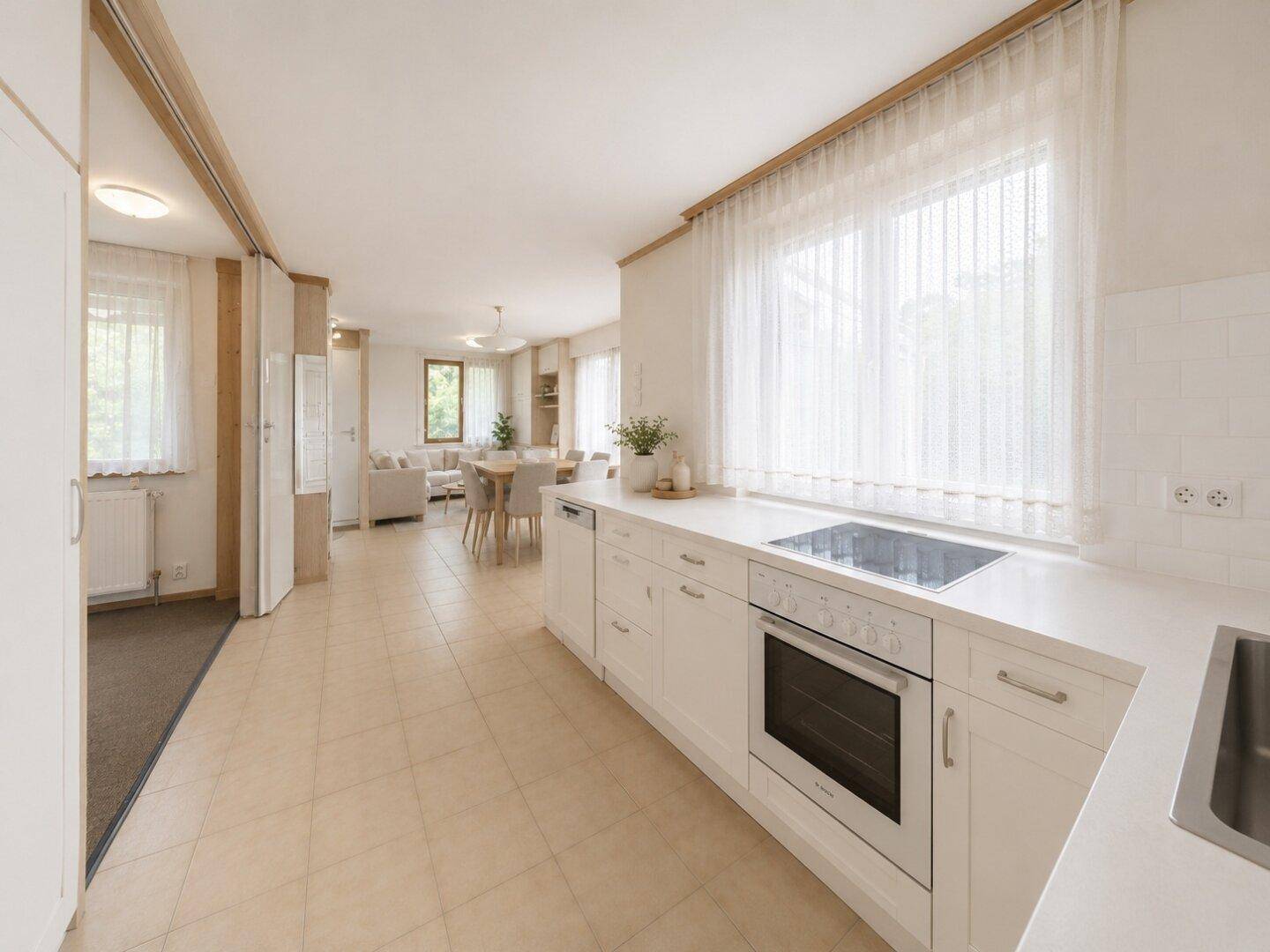 Renovierte Küche mit modernem Herd, weißer Arbeitsplatte und offenem Blick in den Wohnbereich.