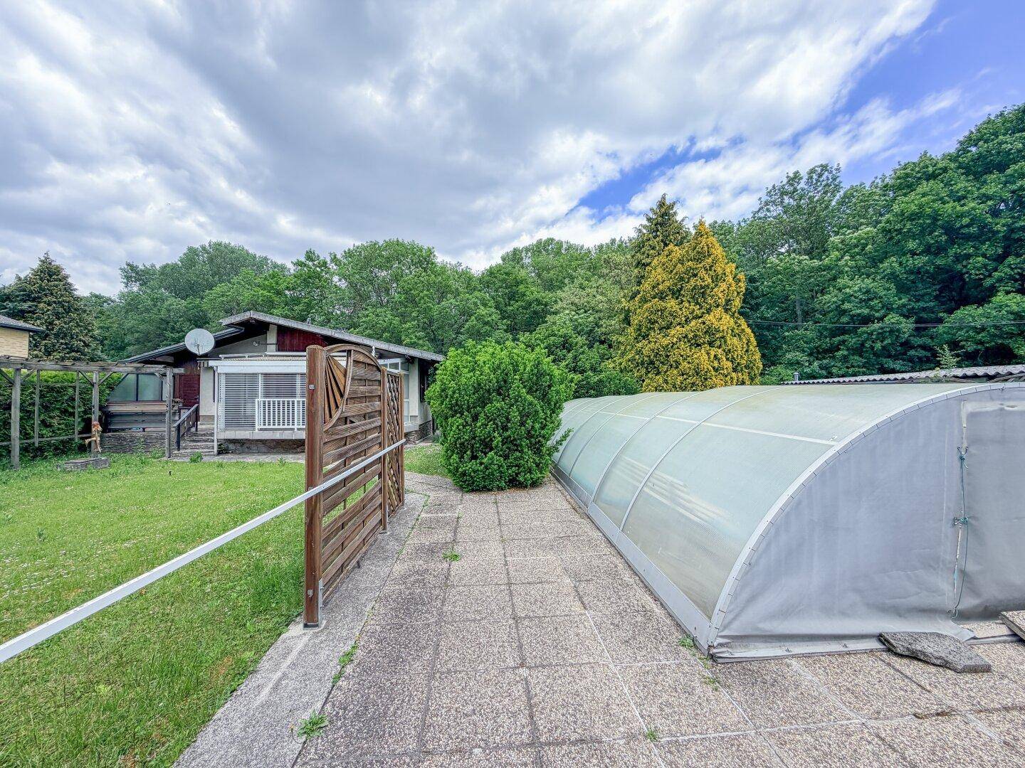 Alter Zustand des Hauses mit gepflastertem Weg und überdachtem Poolbereich im Garten.