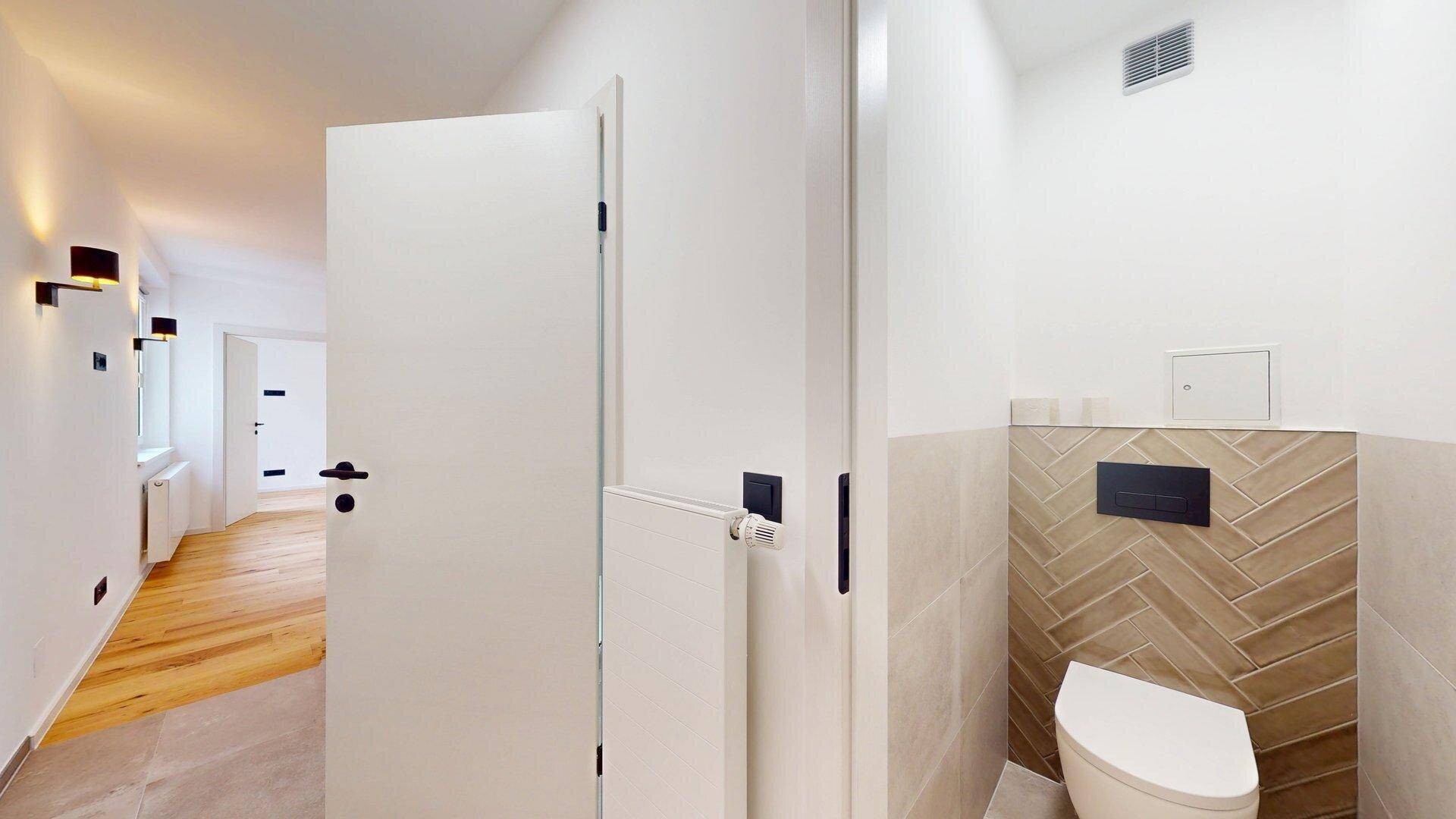 Modernes Gäste-WC mit Wand-WC und stilvollen Fliesen im Fischgrätmuster.