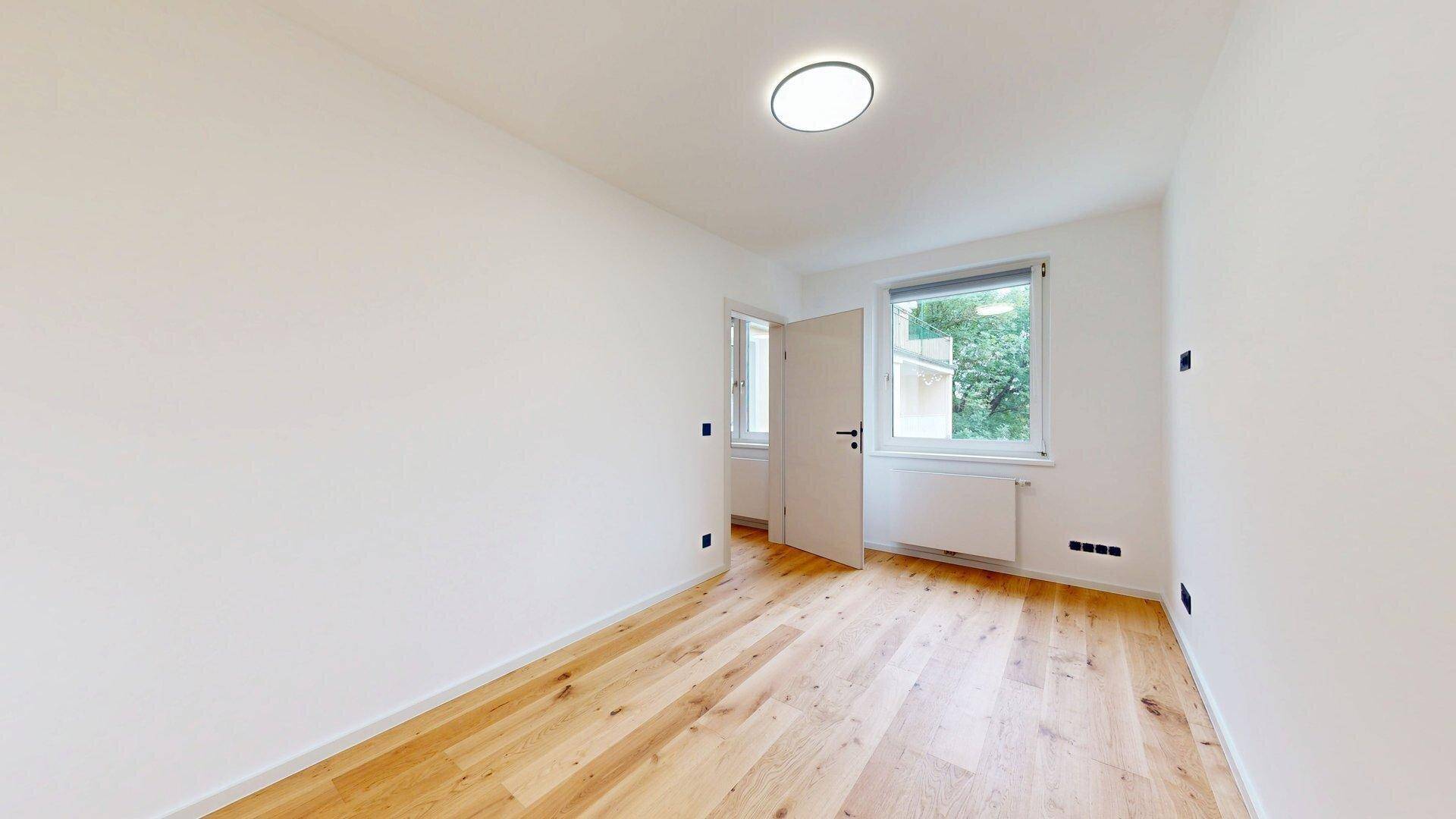 Helles Schlafzimmer mit Holzboden und zwei Fenstern, bietet eine angenehme Wohnatmosphäre.