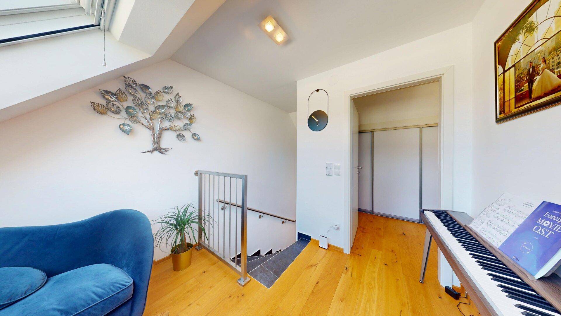 Heller Flur mit Holztreppe, Handlauf und Kunstwerk an der Wand.