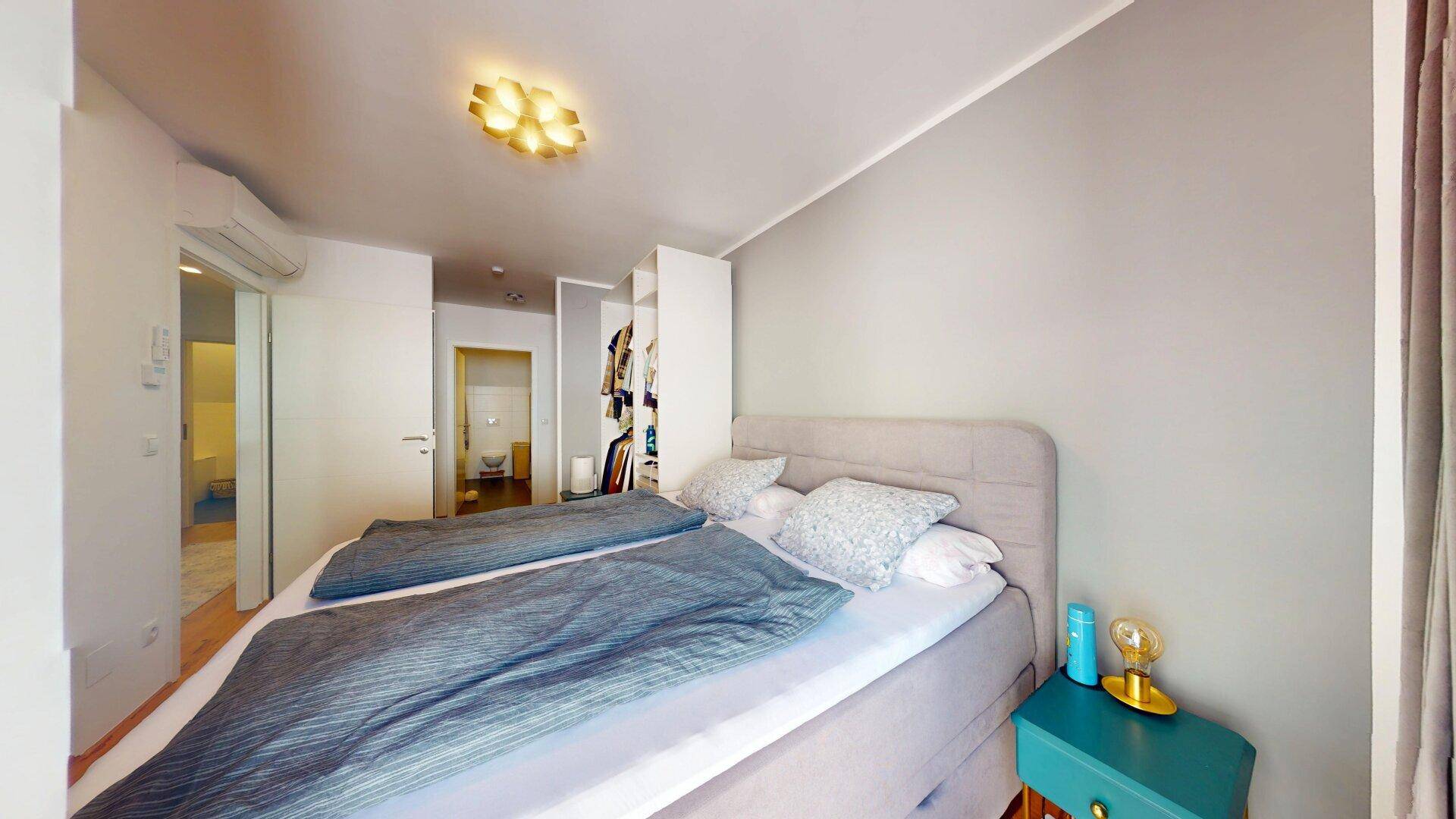 Modernes Schlafzimmer mit Doppelbett, grauen Wänden und Klimaanlage.