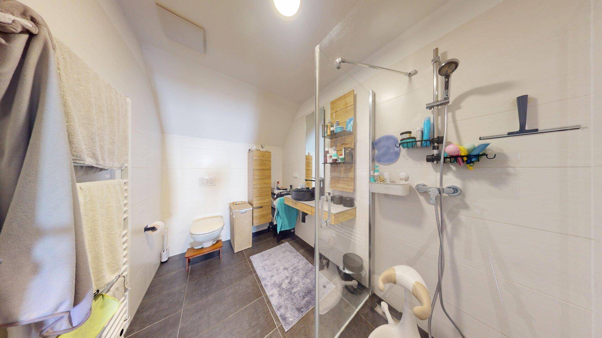 Modernes Badezimmer mit ebenerdiger Dusche, Waschbecken und Holzelementen.
