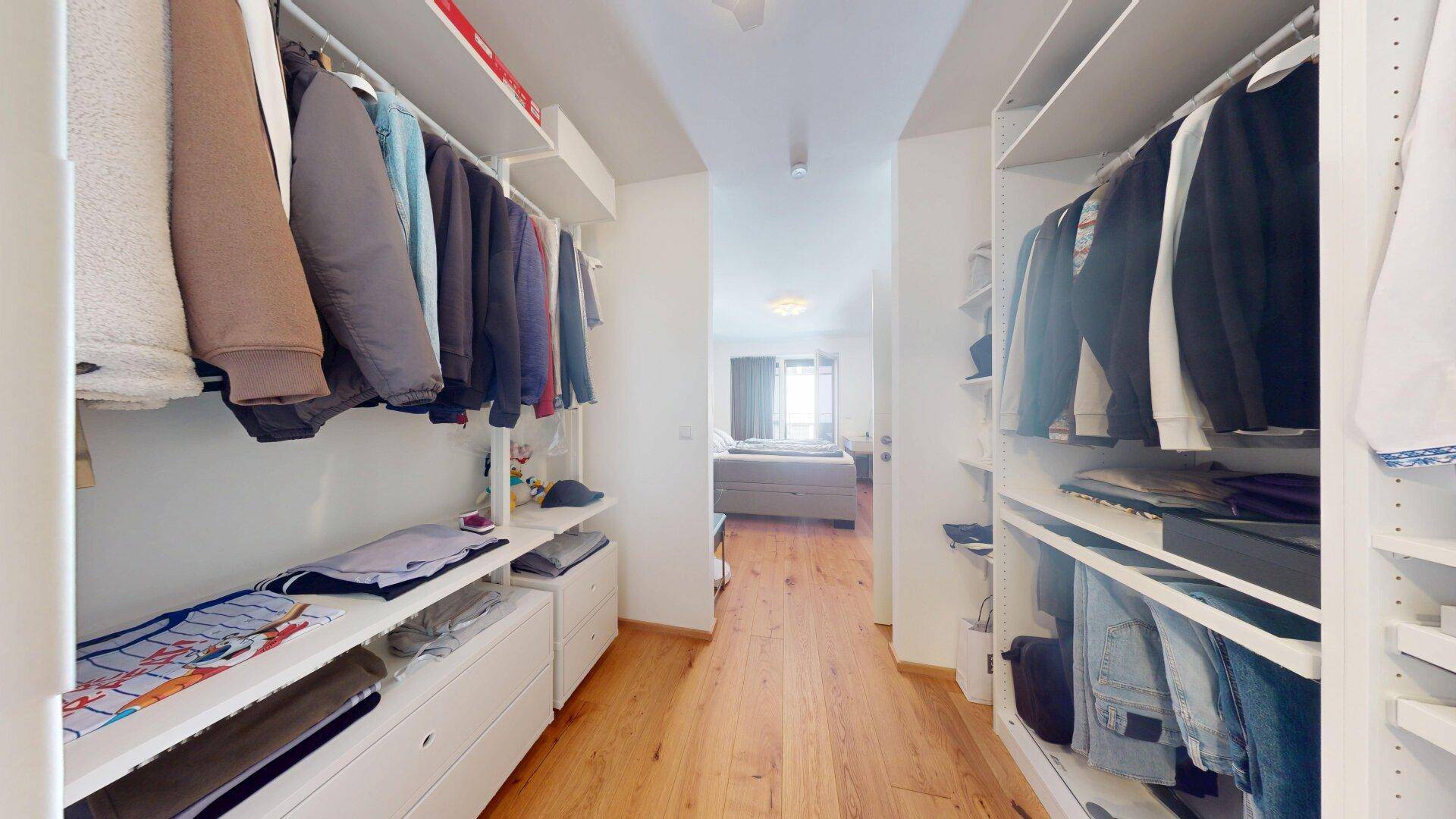 Begehbarer Kleiderschrank mit viel Stauraum und Verbindung zum Schlafzimmer.