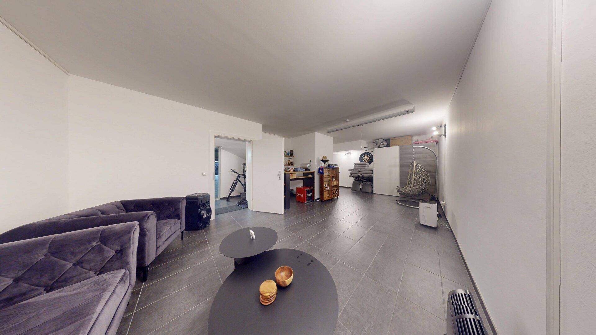 Vielseitiger Kellerraum mit bequemen Sofas und Couchtischen, bietet zusätzlichen Wohn- und Freizeitbereich.