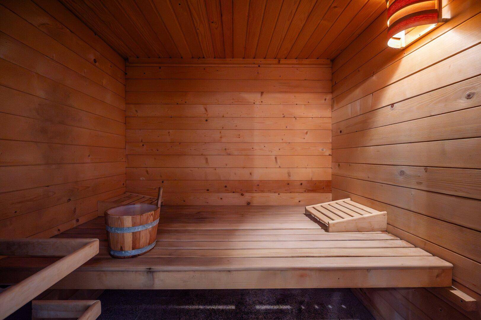 Gemütliche Holzsauna mit Sitzbänken und traditionellem Saunaeimer, ideal zur Entspannung.