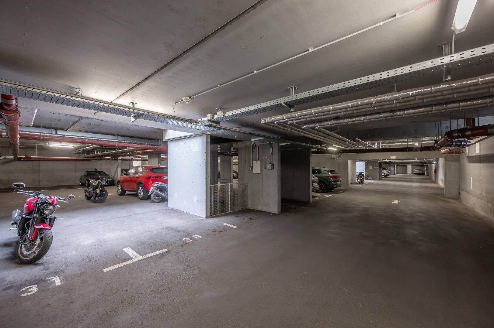 Geräumige Tiefgarage mit mehreren Stellplätzen für Autos und Motorräder.