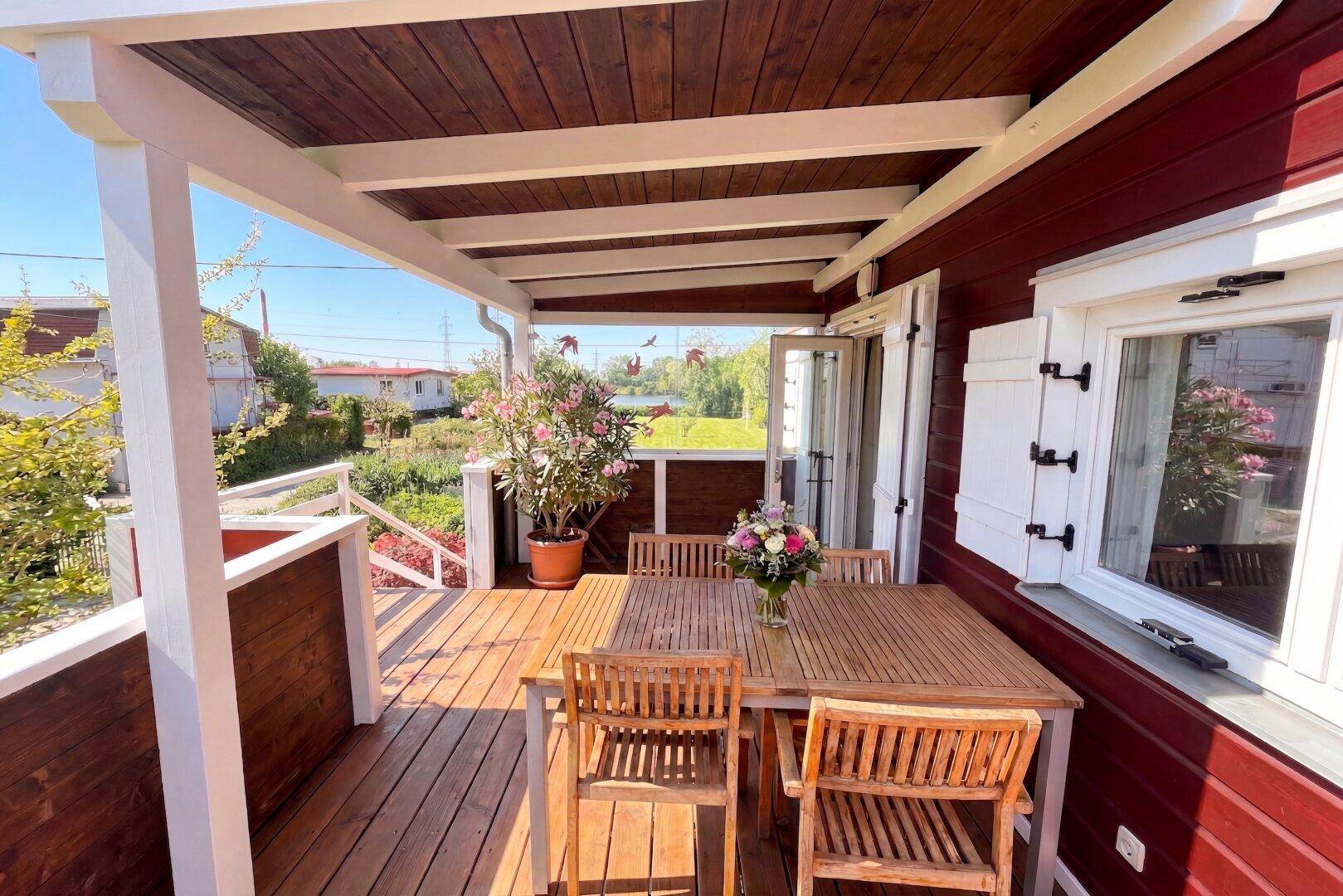 Gemütlicher Balkon mit Holzboden und -möbeln, ideal für Mahlzeiten im Freien mit Blick ins Grüne.
