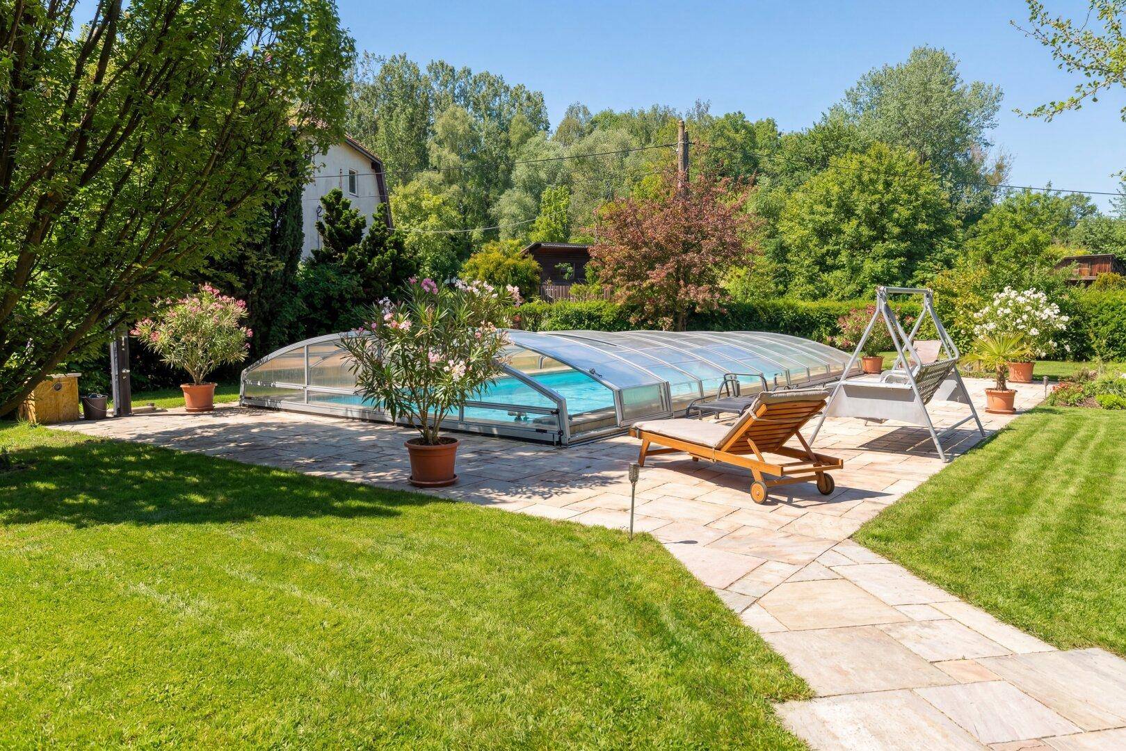 Großer, gepflegter Garten mit überdachtem Pool, Sonnenterrasse und viel Grünfläche zum Entspannen.