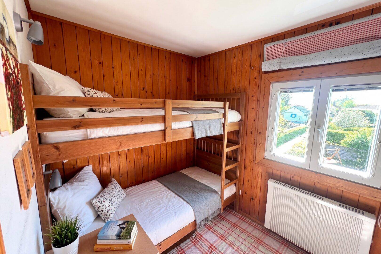 Gemütliches Schlafzimmer mit Etagenbett und Holzvertäfelung, ideal als Kinder- oder Gästezimmer.