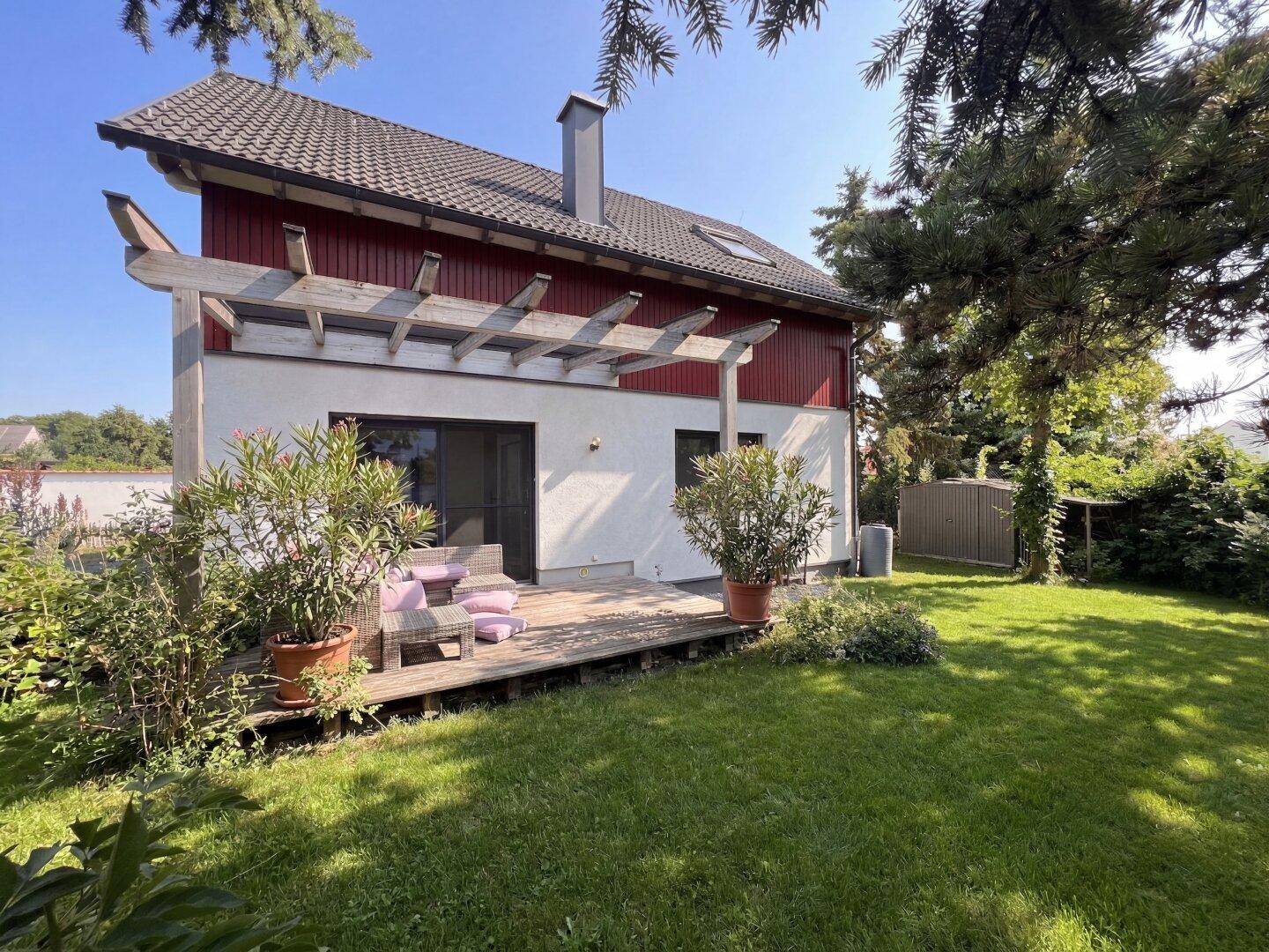 Rückseite des Hauses mit Holzterrasse, Gartenmöbeln und großem Gartenbereich.