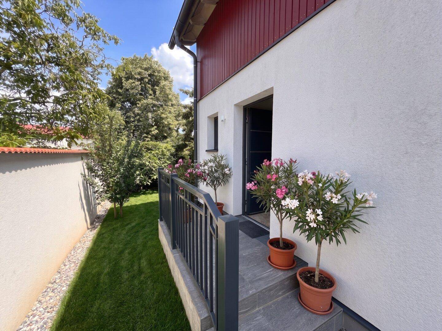 Eingangsbereich des Hauses mit Treppe, Geländer und blühenden Oleanderpflanzen.