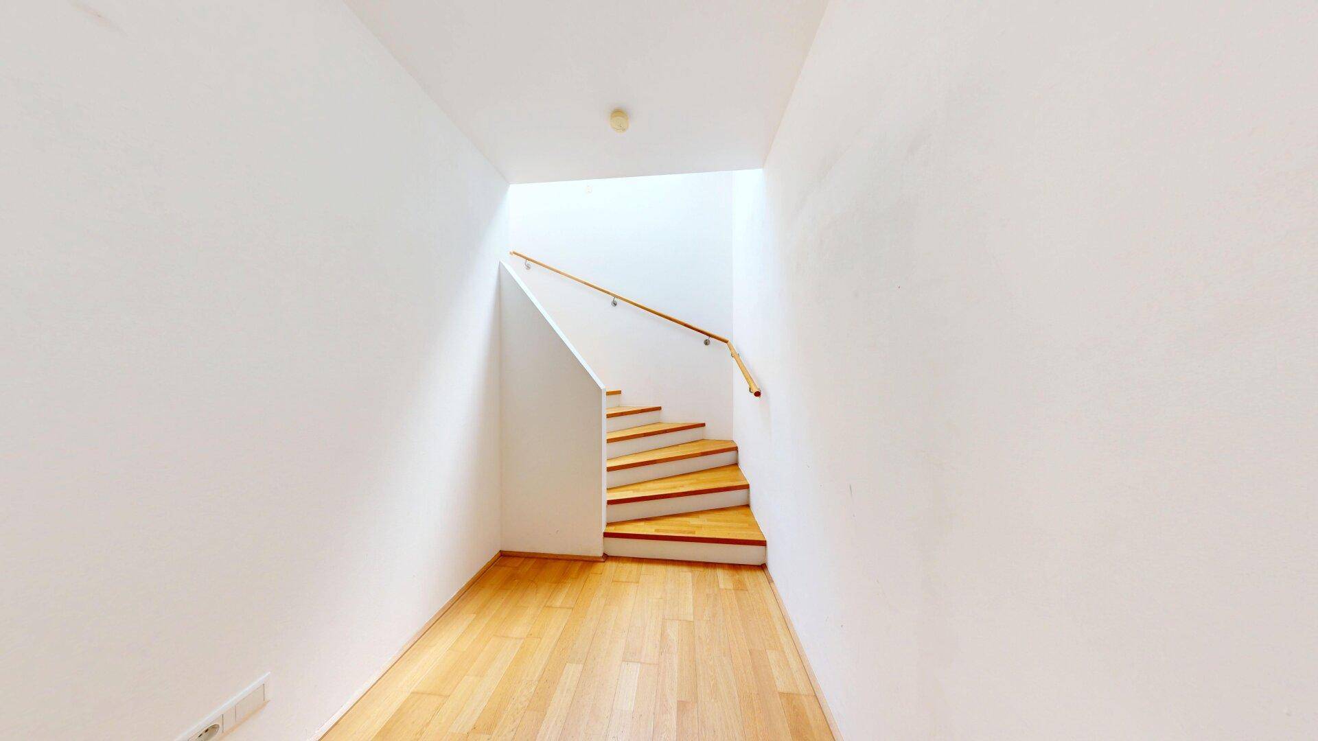 Heller Flur mit Holztreppe, die in die obere Etage führt.