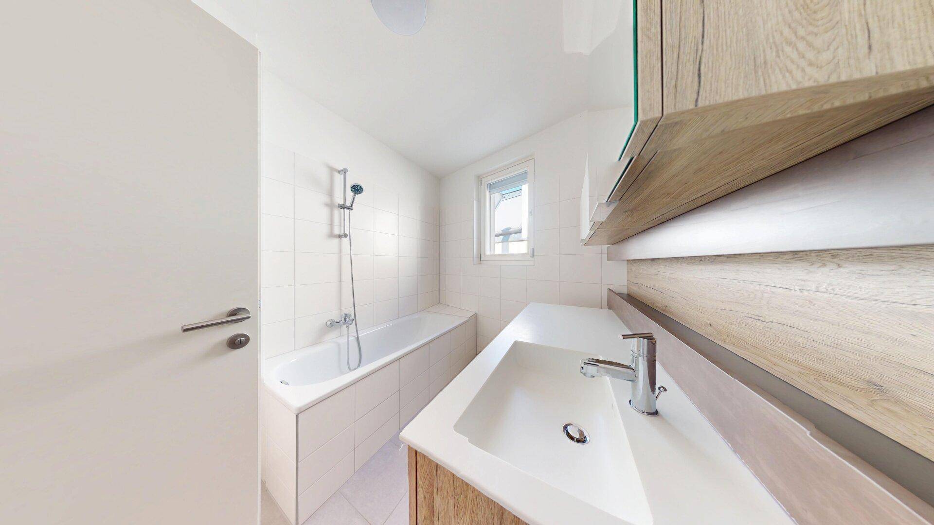 Modernes Badezimmer mit Badewanne, Einzelwaschbecken und Holzunterschrank.
