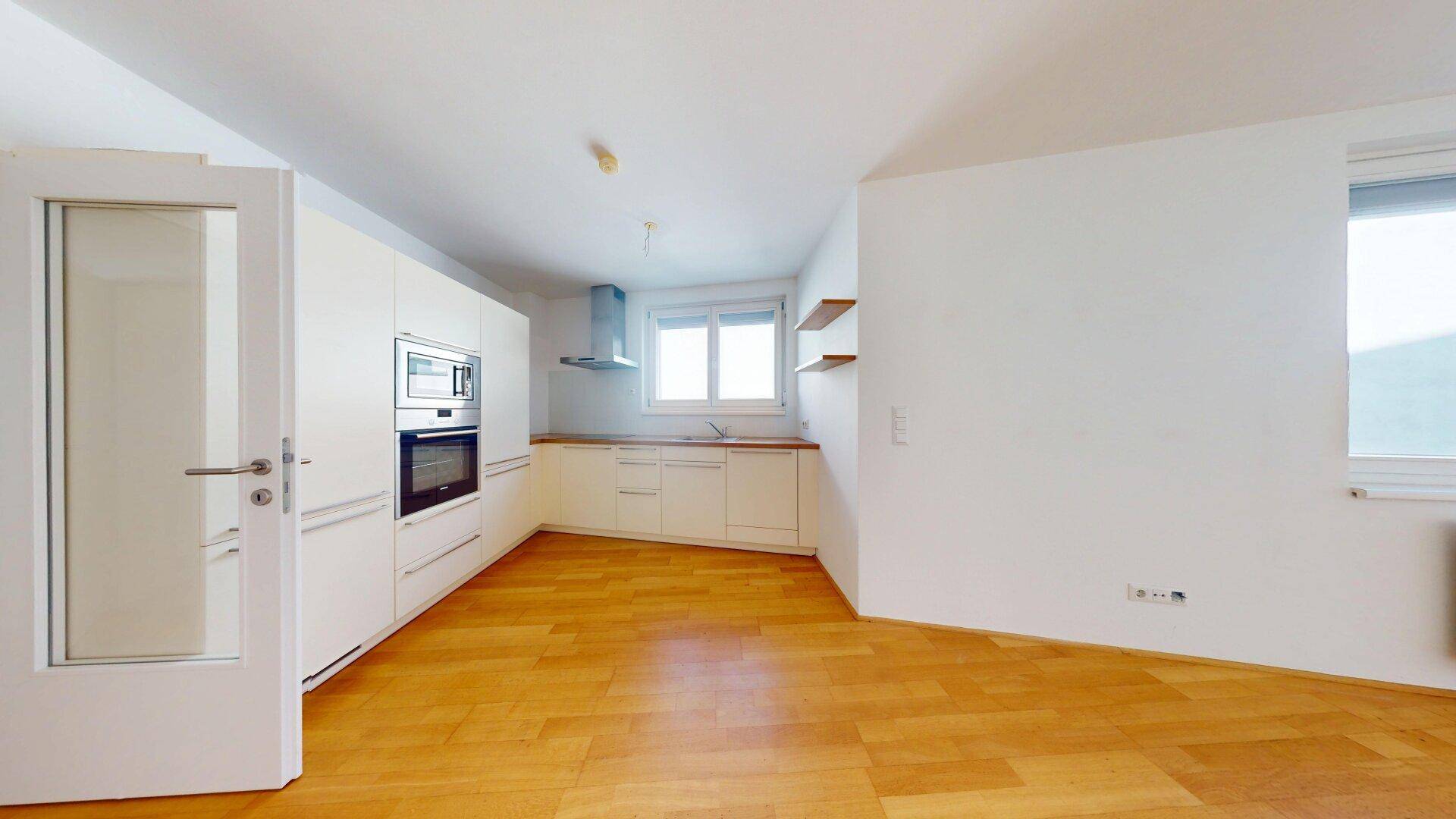 Moderne Einbauküche mit weißen Schränken, Holztheke und integrierten Geräten.