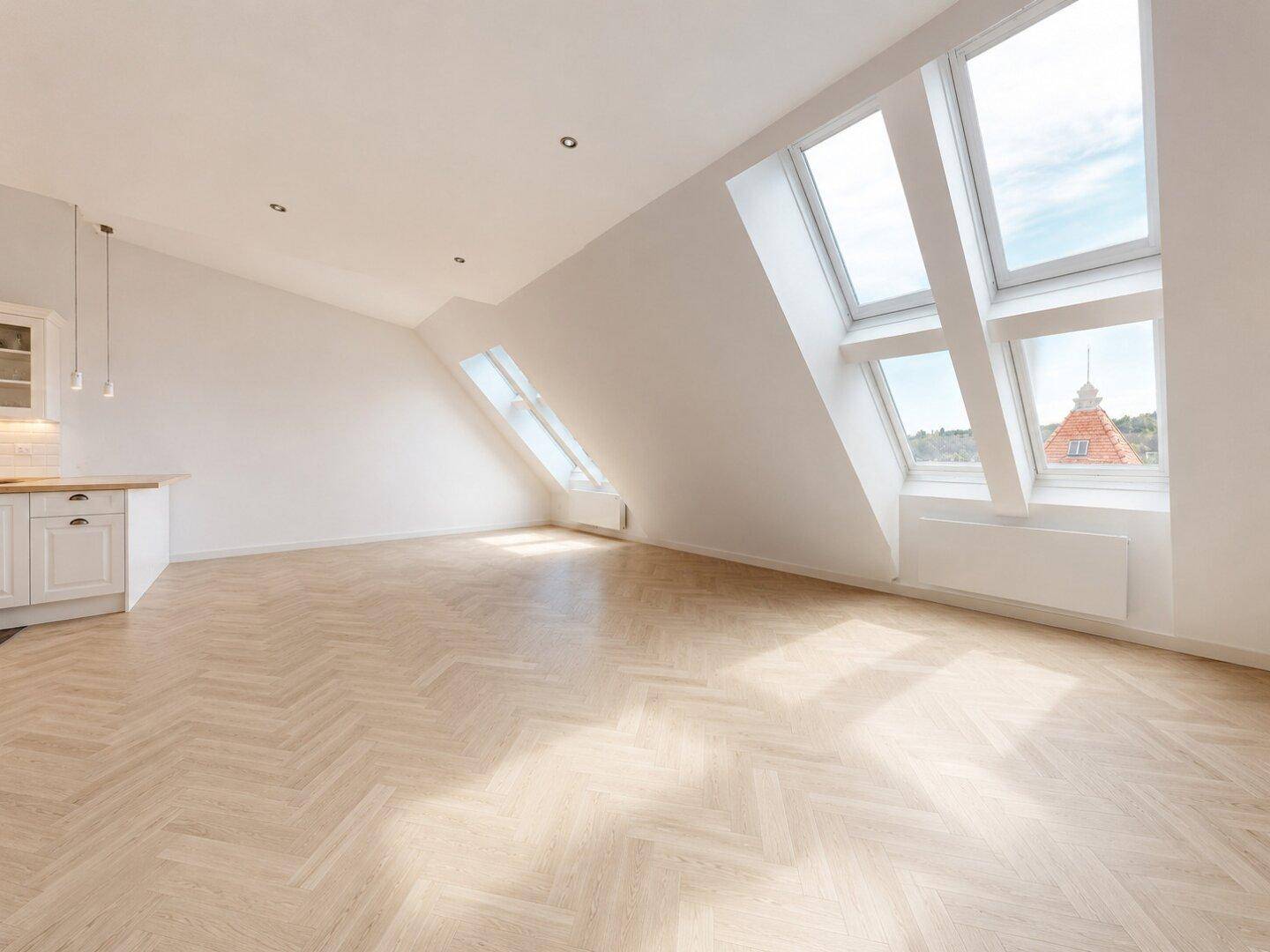 Helles Dachgeschosszimmer mit Fischgrätparkett und großen Dachfenstern, die viel Licht hereinlassen.