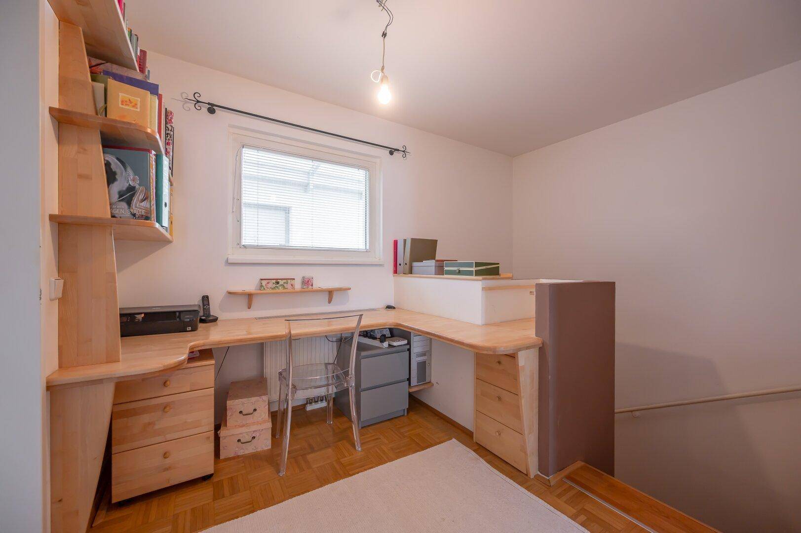 Funktionales Arbeitszimmer mit Holzschreibtisch, Regalen und Parkettboden, ideal für Home-Office.