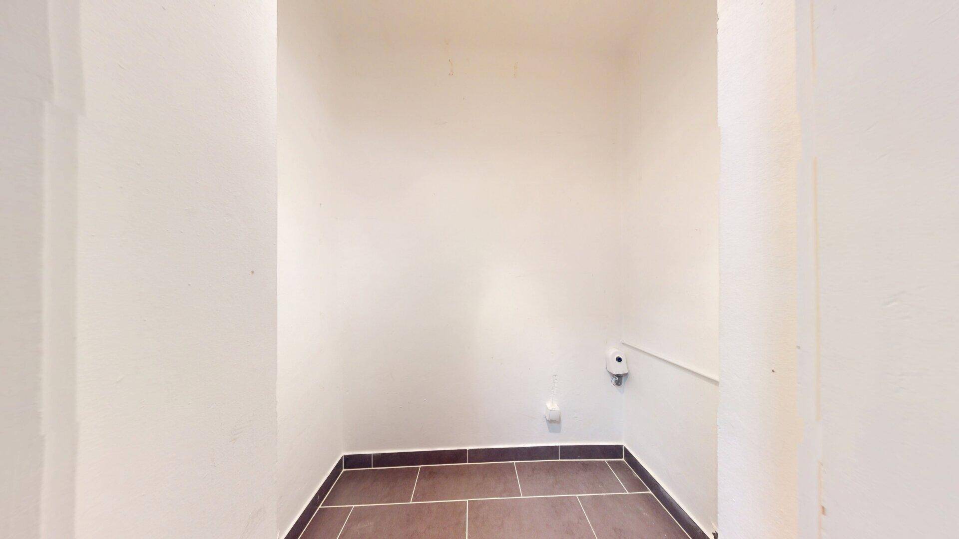 Kleiner Abstellraum mit Fliesenboden und Steckdose, ideal für Lagerzwecke oder als Hauswirtschaftsraum.