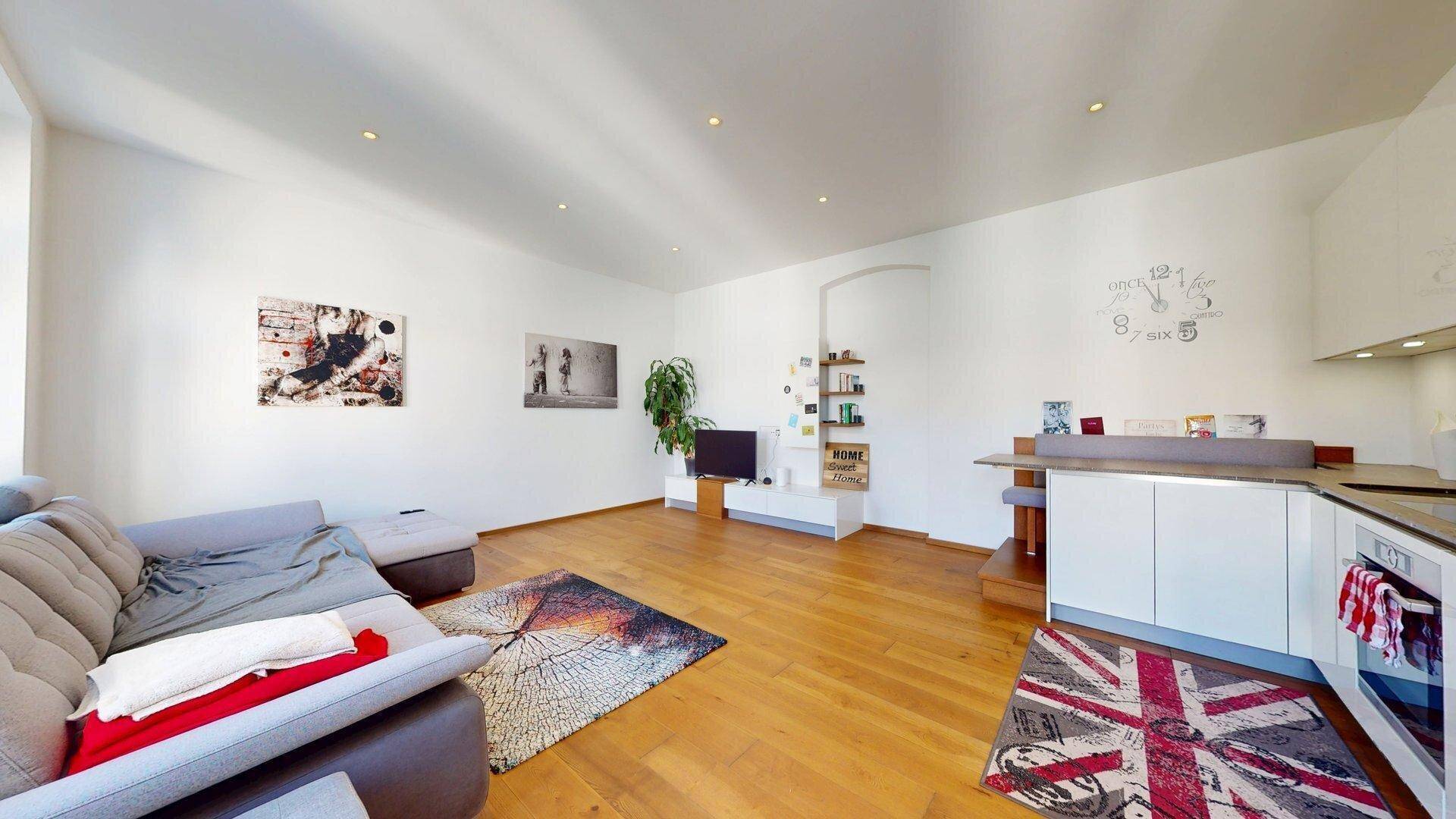 Geräumiger Wohnbereich mit Holzboden, bequemer Couch und moderner Dekoration.