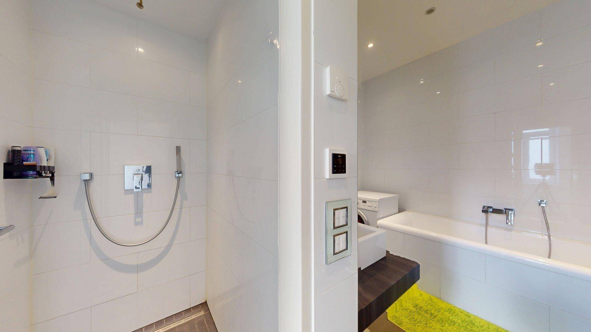 Modernes Badezimmer mit weiß gefliesten Wänden, Badewanne und separater Dusche.