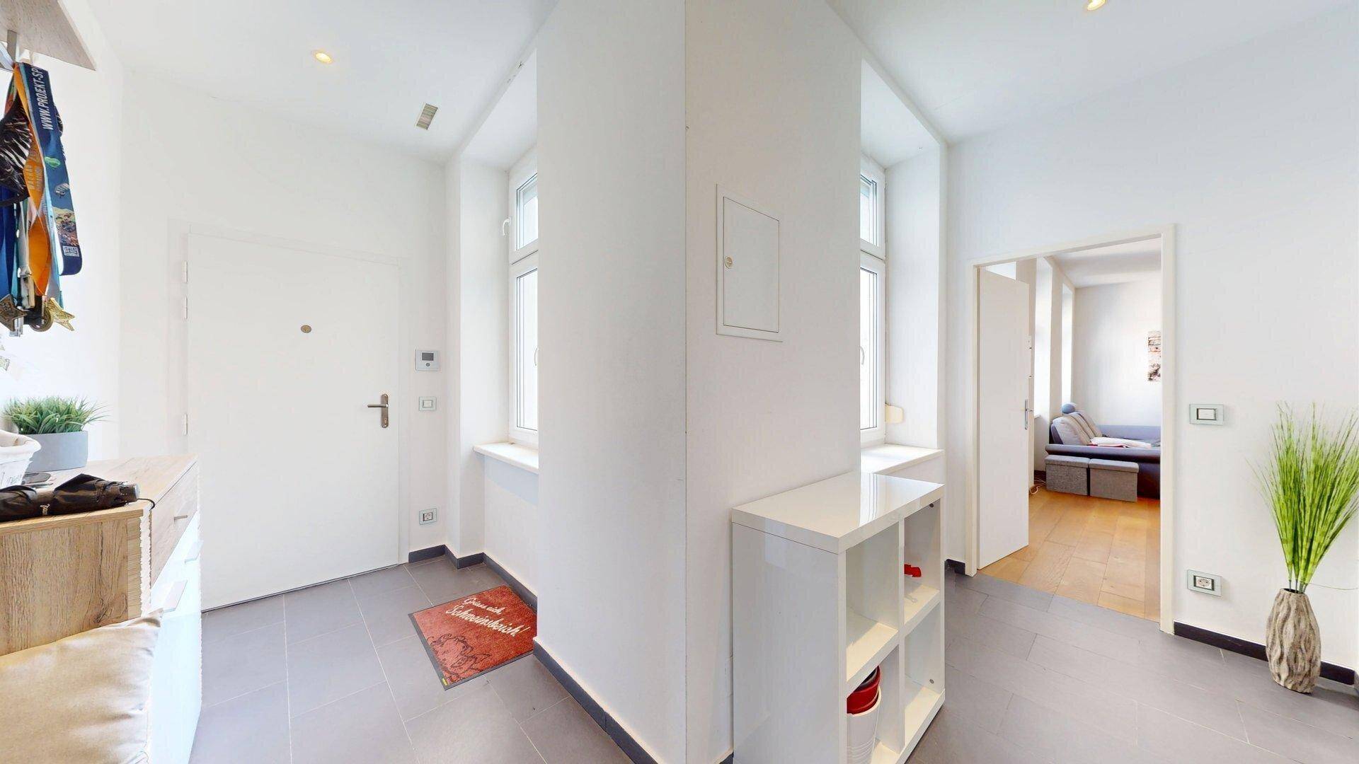 Heller Eingangsbereich mit Fliesenboden, Garderobe und Zugang zu weiteren Räumen.