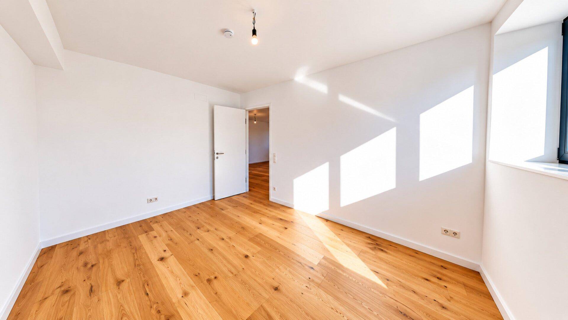Sonniger Schlafbereich mit Holzboden und weißen Wänden, ideal für ein gemütliches Ambiente.