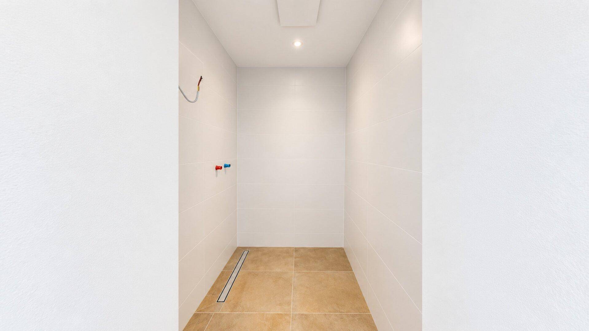 Modernes Badezimmer mit Fliesenboden und vorbereitetem Duschbereich, minimalistisches Design.