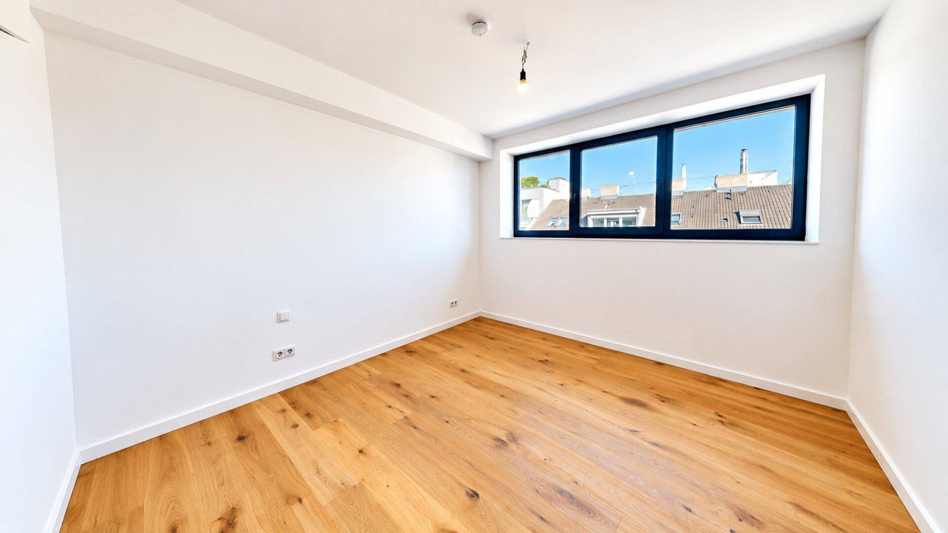 Schlafzimmer mit Holzboden und großem Fenster, das einen weiten Blick über die Stadt bietet.