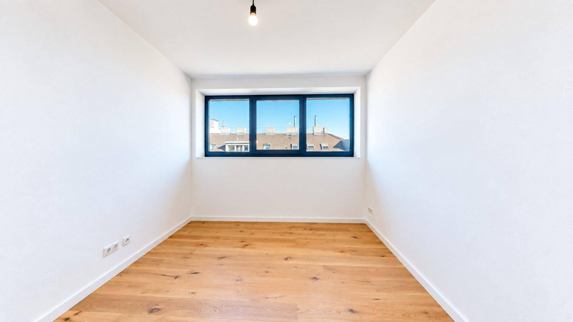 Helles Schlafzimmer mit Holzboden und Fenster, das einen klaren Blick auf die Umgebung ermöglicht.