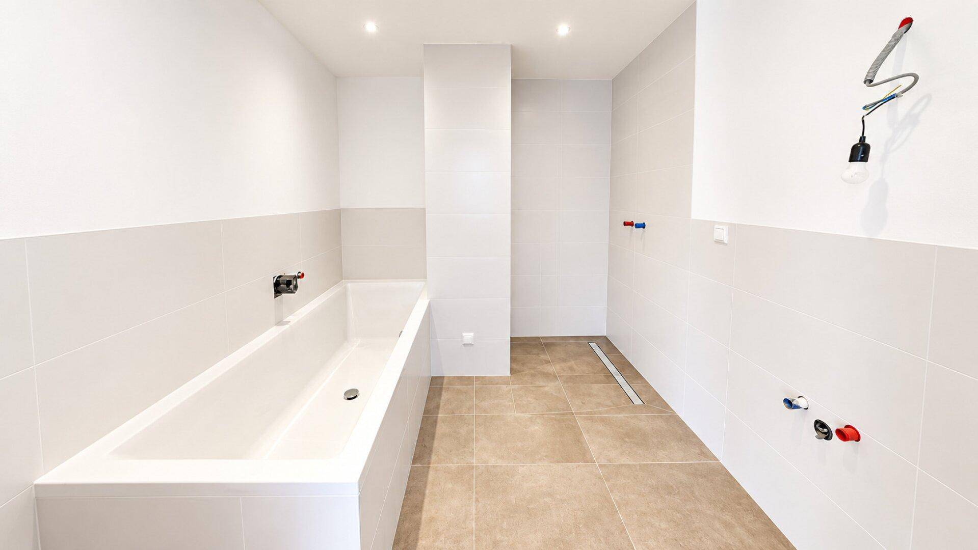 Geräumiges Badezimmer mit Badewanne und Duschbereich, hell gefliest und modern.