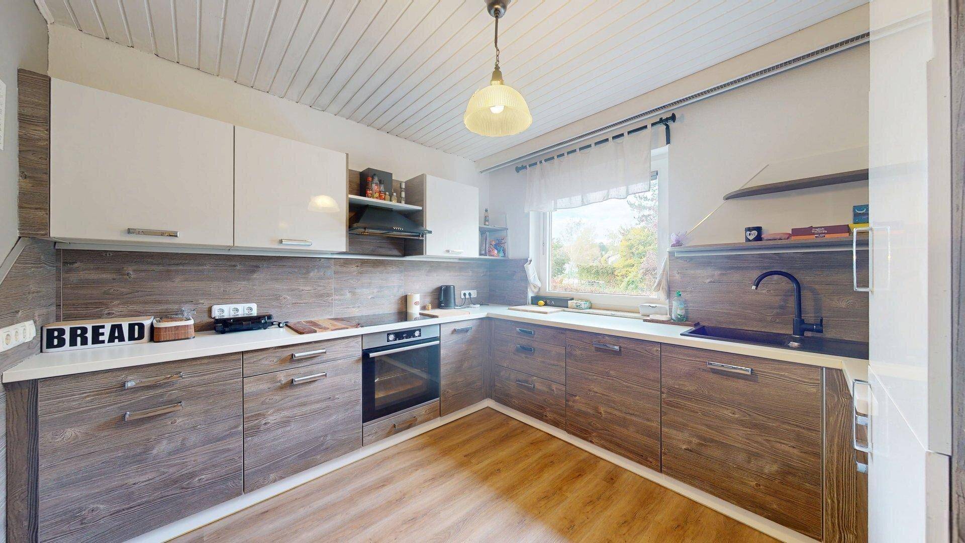 Moderne Küche mit Holz- und weißen Fronten, integrierten Geräten und Fensterblick.