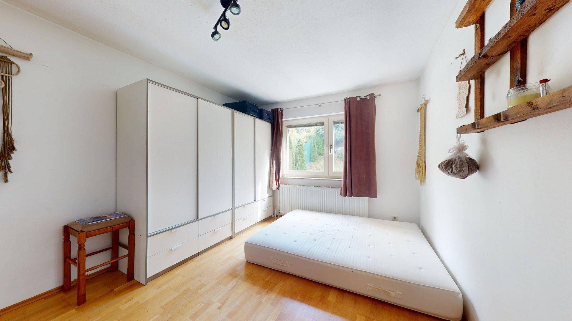 Schlafzimmer mit großem Kleiderschrank, Holzboden und Fenster mit Blick ins Grüne.