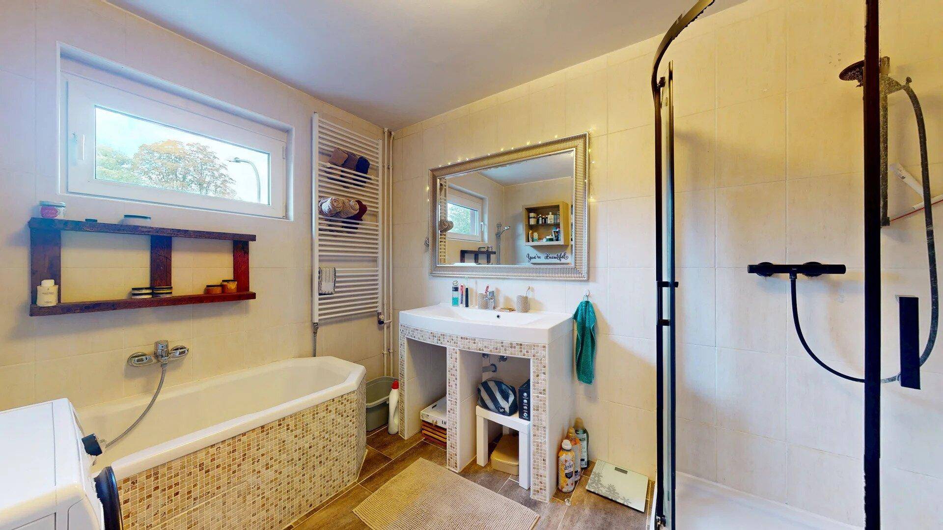 Helles Badezimmer mit Badewanne, separater Dusche, Waschbecken und Fenster.