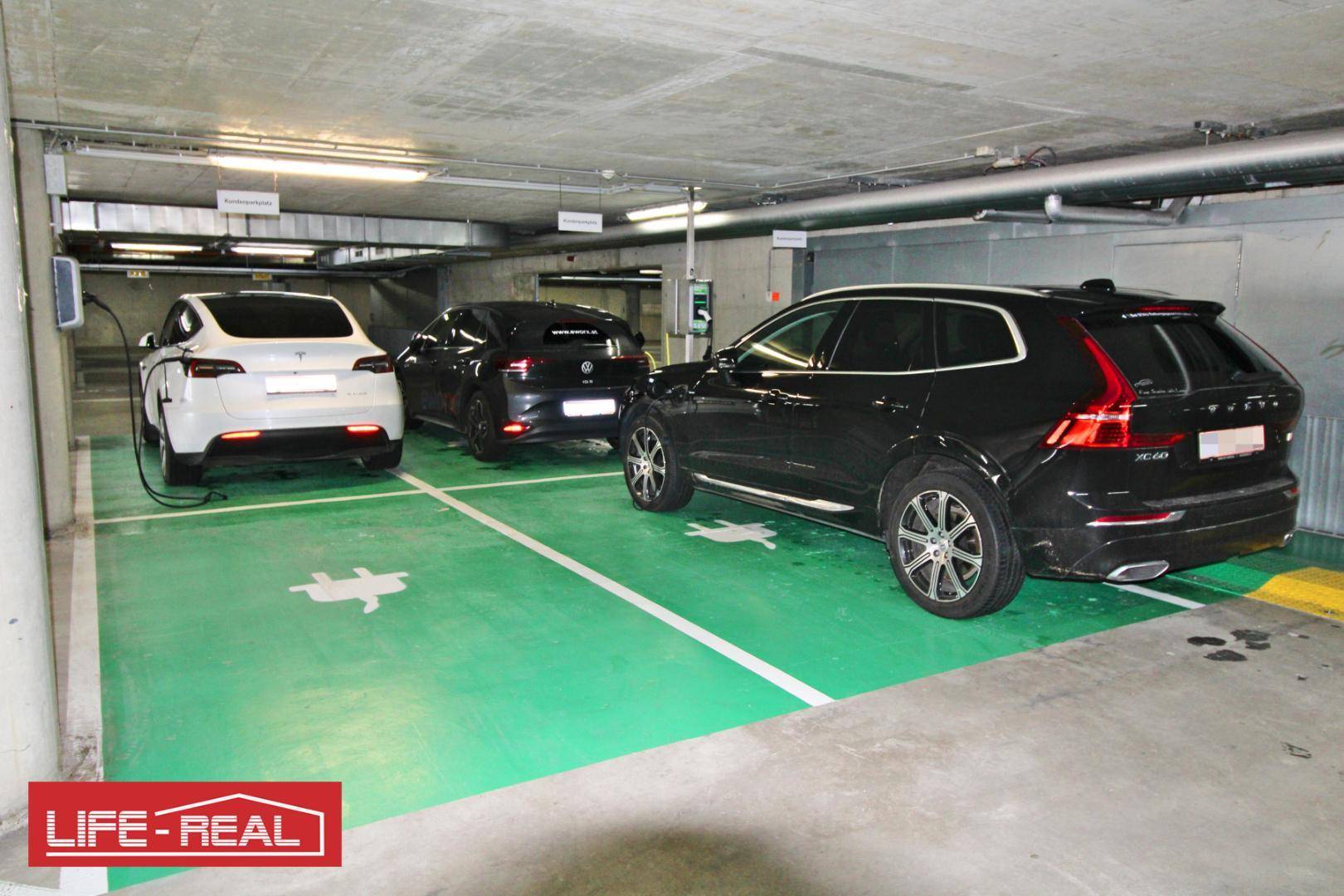 Moderne Tiefgarage mit markierten Stellplätzen und mehreren Ladestationen für Elektrofahrzeuge.