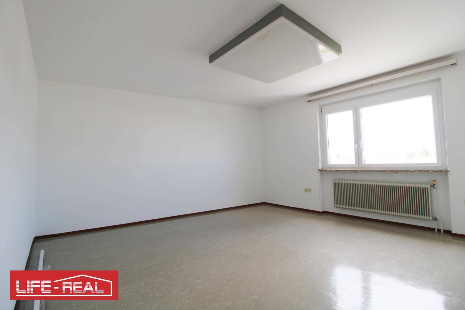 Heller, leerer Raum mit großem Fenster und Heizkörper, ideal für individuelle Gestaltungsmöglichkeiten.