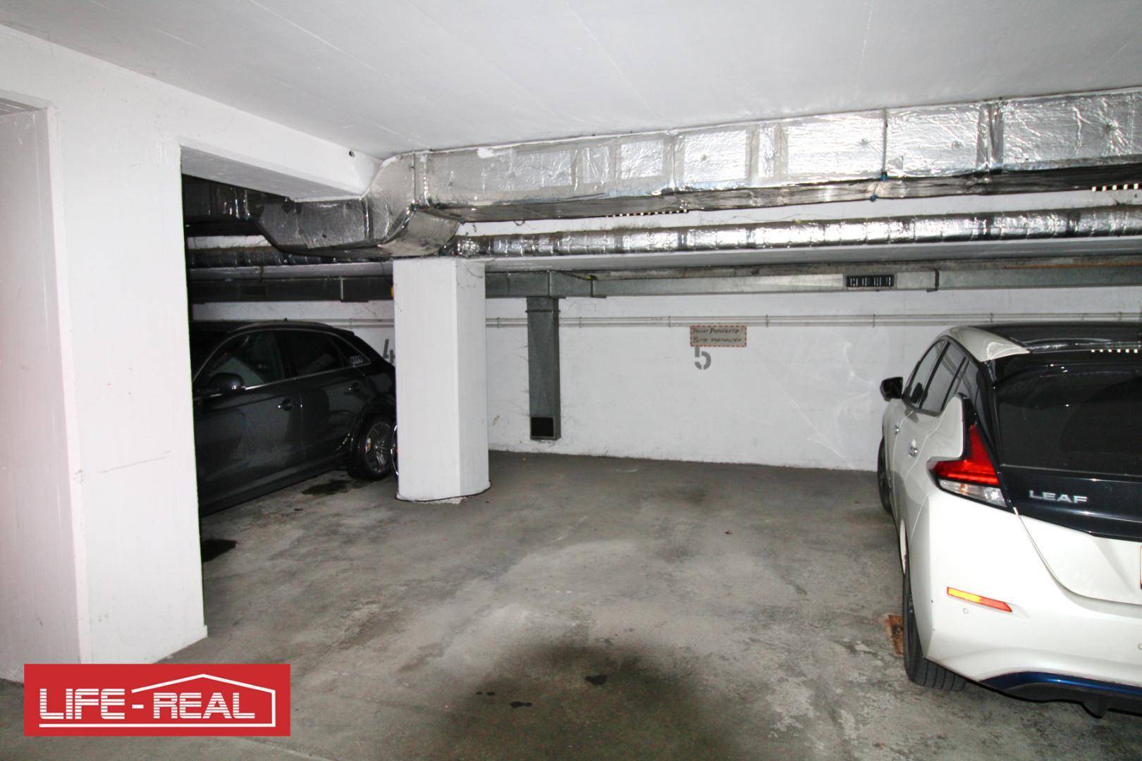 Einzelner Stellplatz in der Tiefgarage mit sichtbaren Leitungen an der Decke.