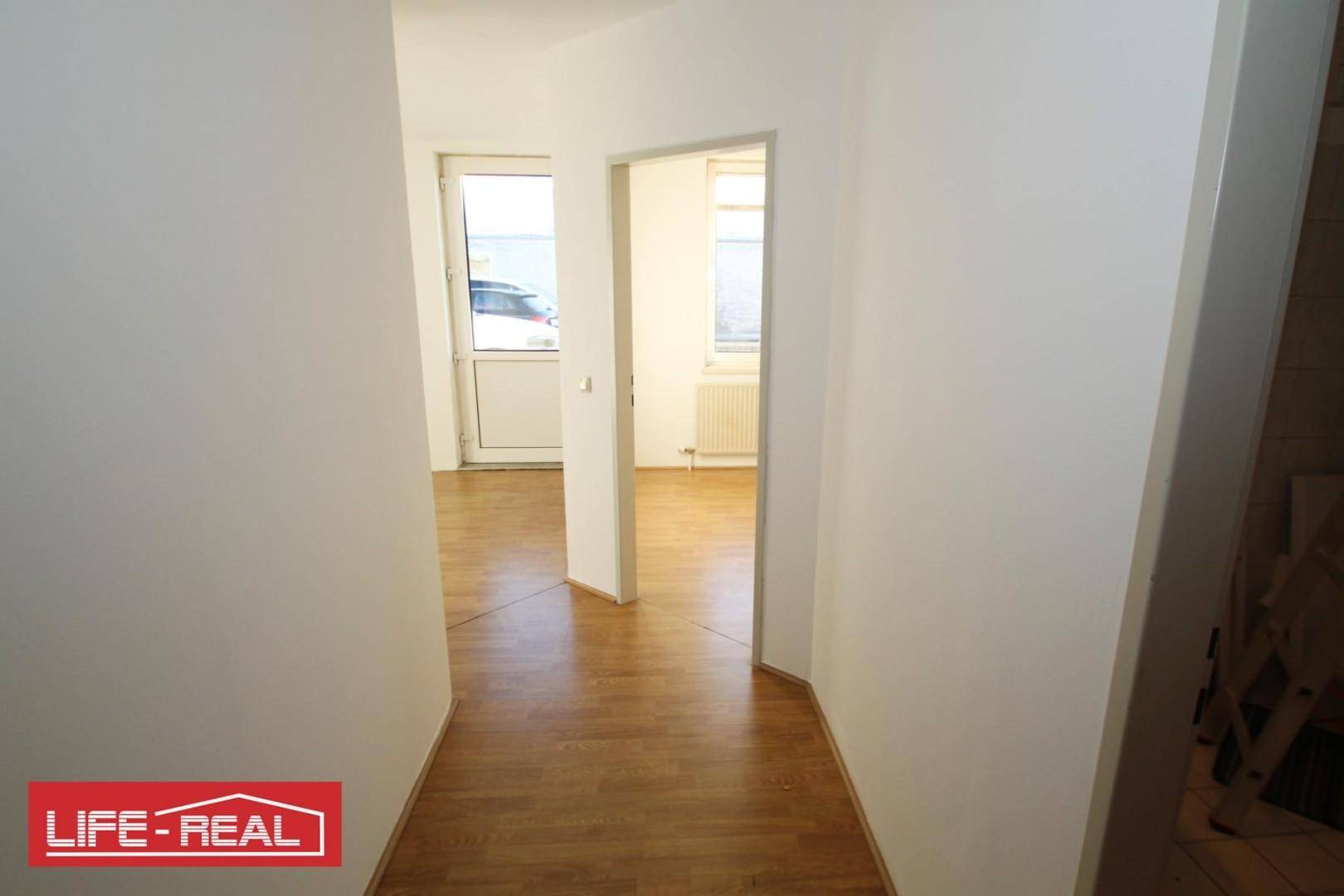 Heller Flur mit Laminatboden, weißen Wänden und Türen, die zu verschiedenen Räumen führen.