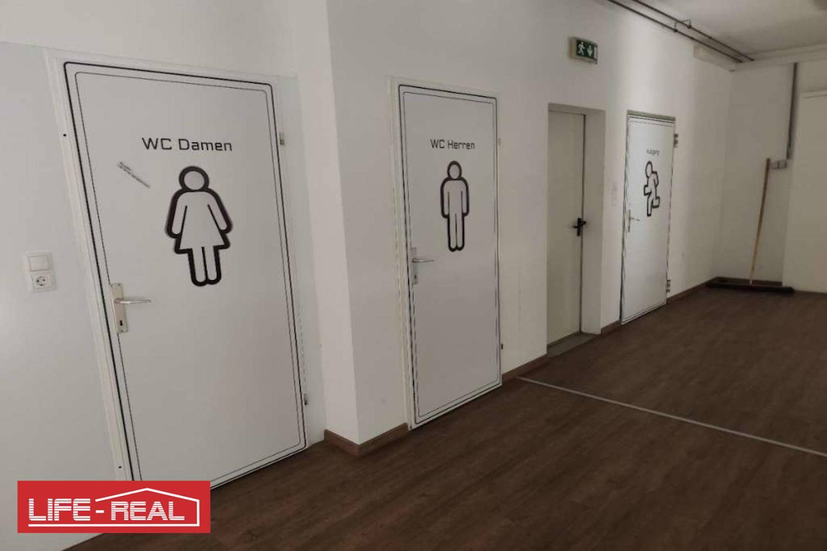 Flur mit separaten Toiletten für Damen und Herren, gekennzeichnet mit Piktogrammen.