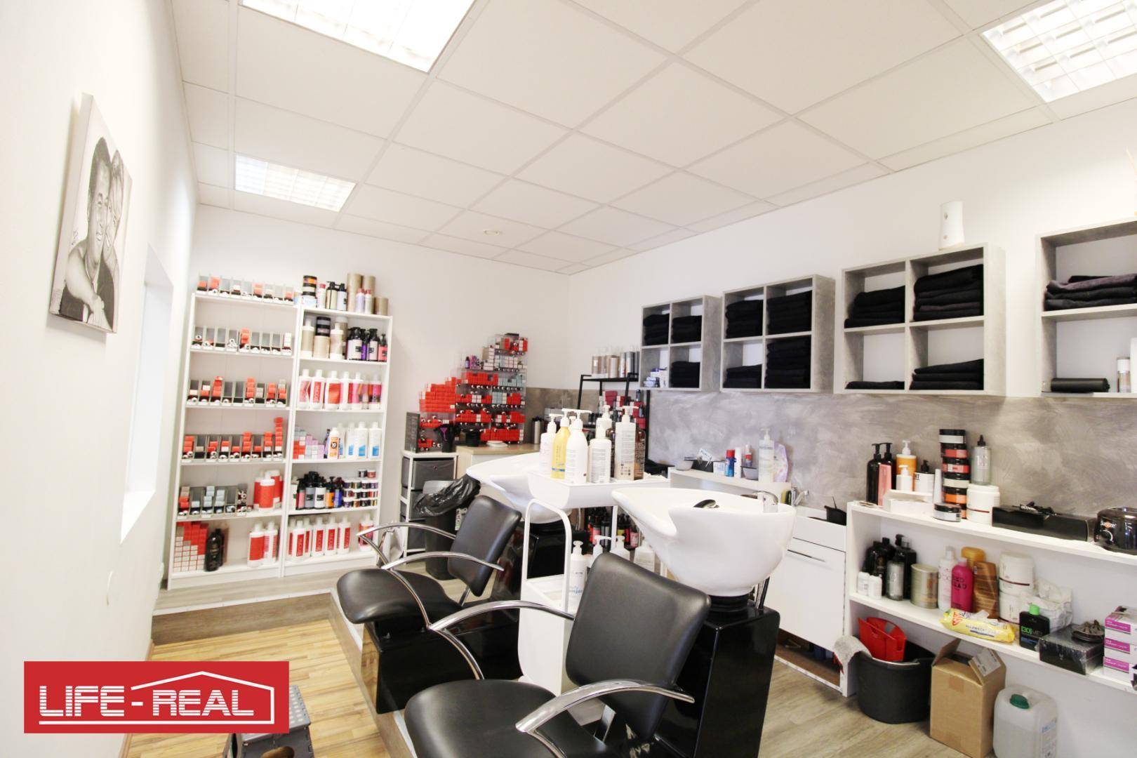 Innenansicht eines Friseursalons mit mehreren Waschbecken, Regalen voller Produkte und Arbeitsstühlen.