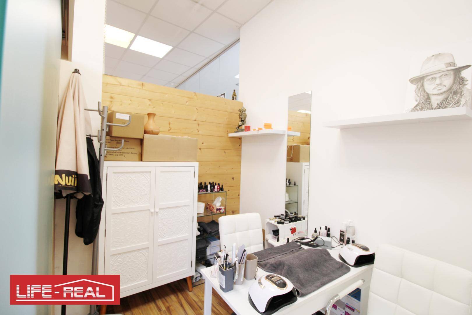 Bereich für Nagelpflege oder Kosmetik mit Arbeitstisch, Stuhl und Holzverkleidung an der Wand.