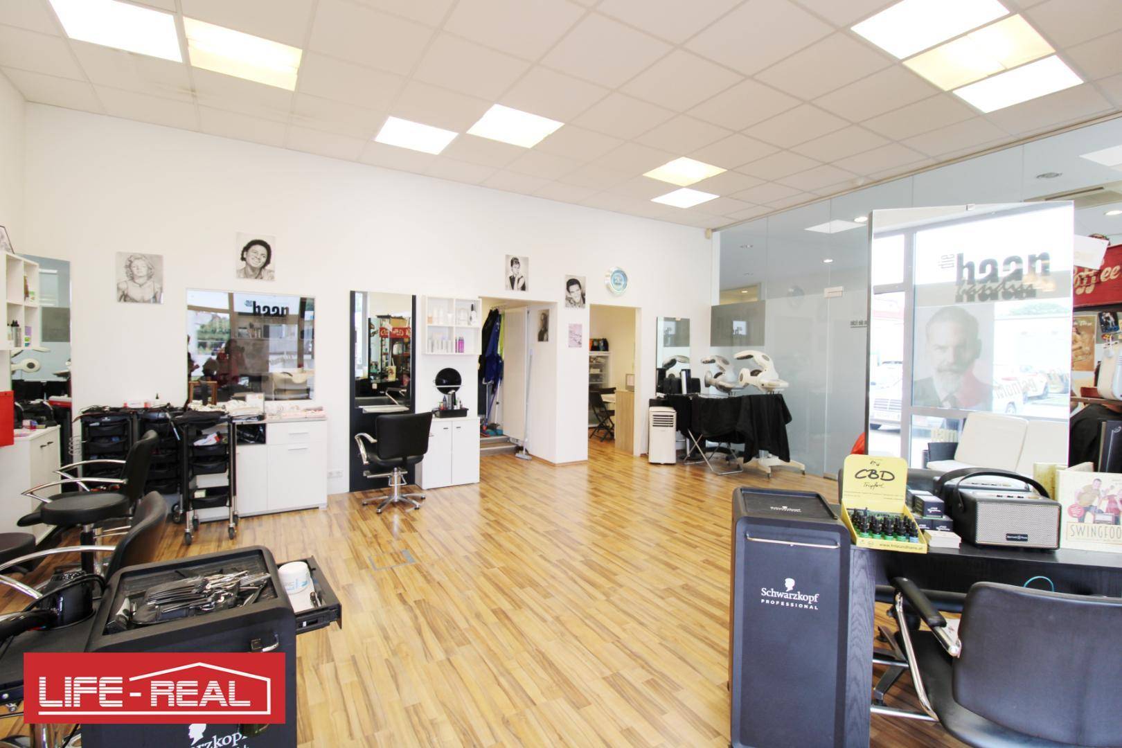 Heller Friseursalon mit vielen Arbeitsplätzen, Produktregalen und großen Fenstern zur Straße.
