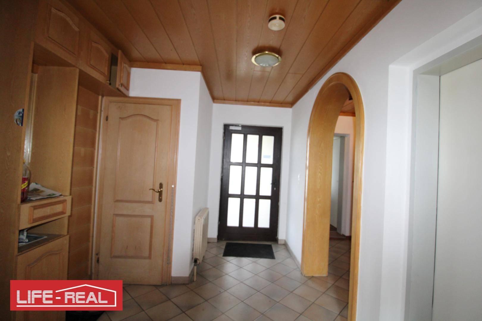 Eingangsbereich mit Holzdecke, Fliesenboden und Garderobenschrank, einladend gestaltet.