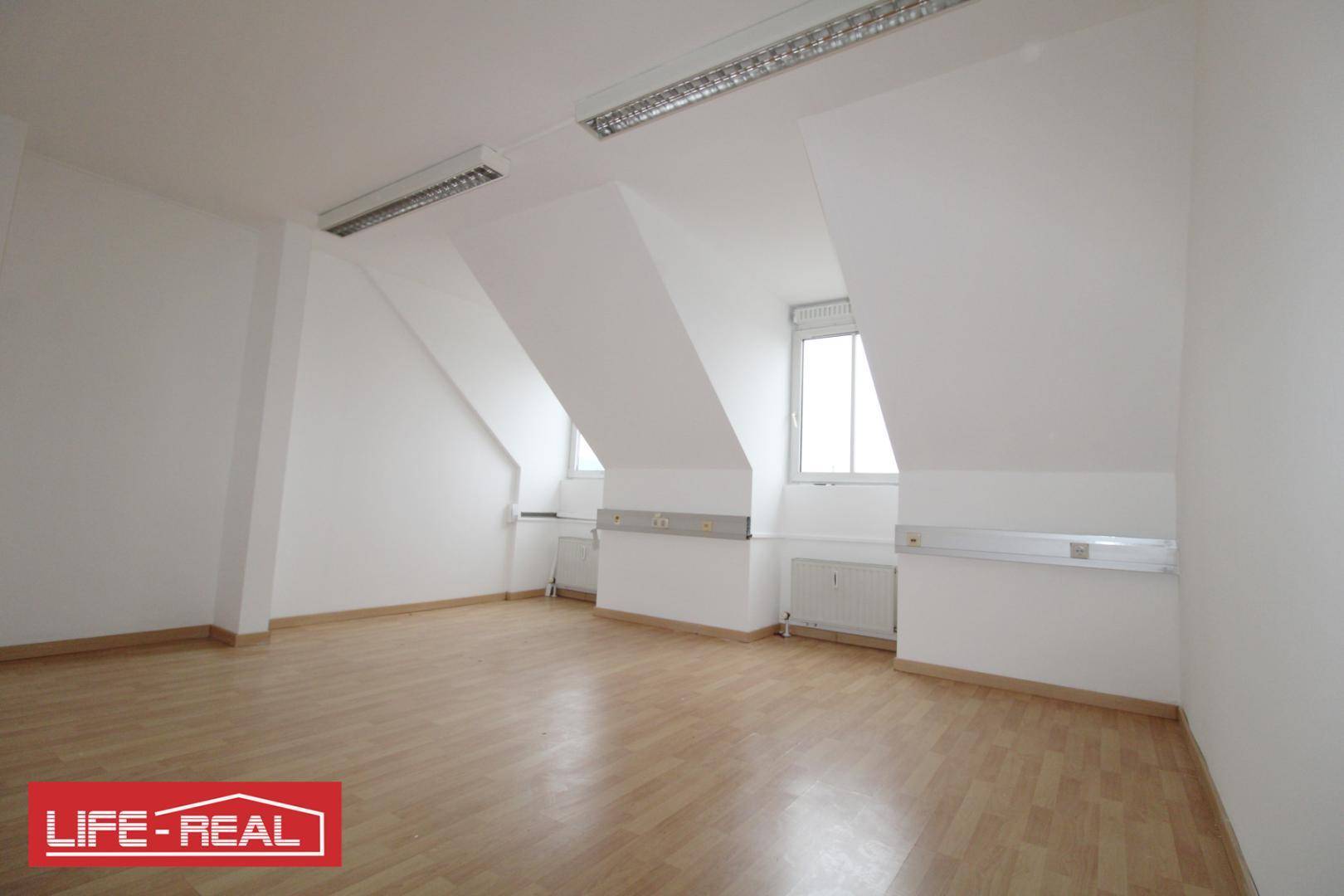 Geräumiger Dachraum mit schrägen Wänden, hellen Fenstern und Laminatboden, bietet vielseitige Nutzungsmöglichkeiten.