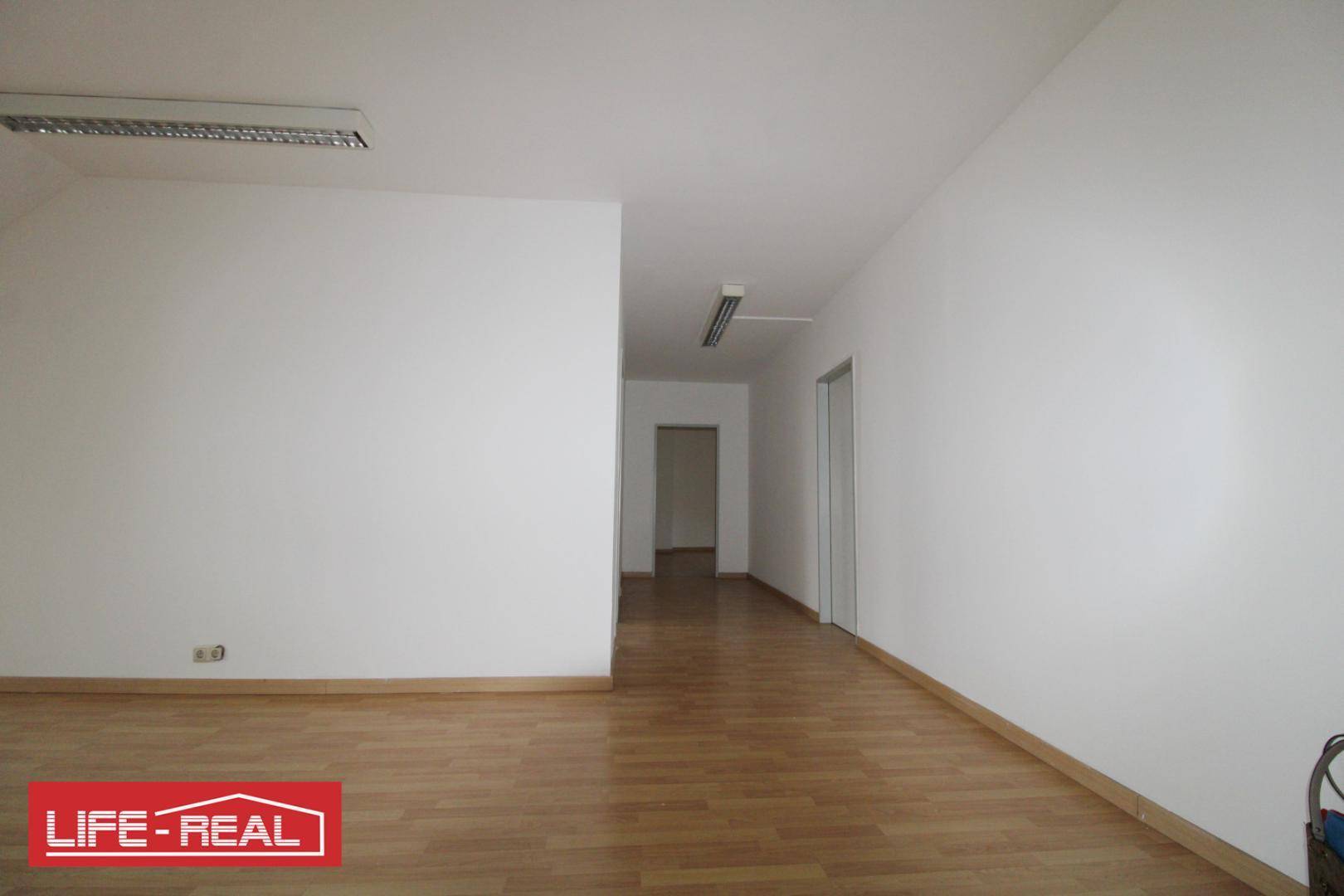 Geräumiger, leerer Raum mit Laminatboden und weiß gestrichenen Wänden, ideal für Büro oder Wohnzwecke.